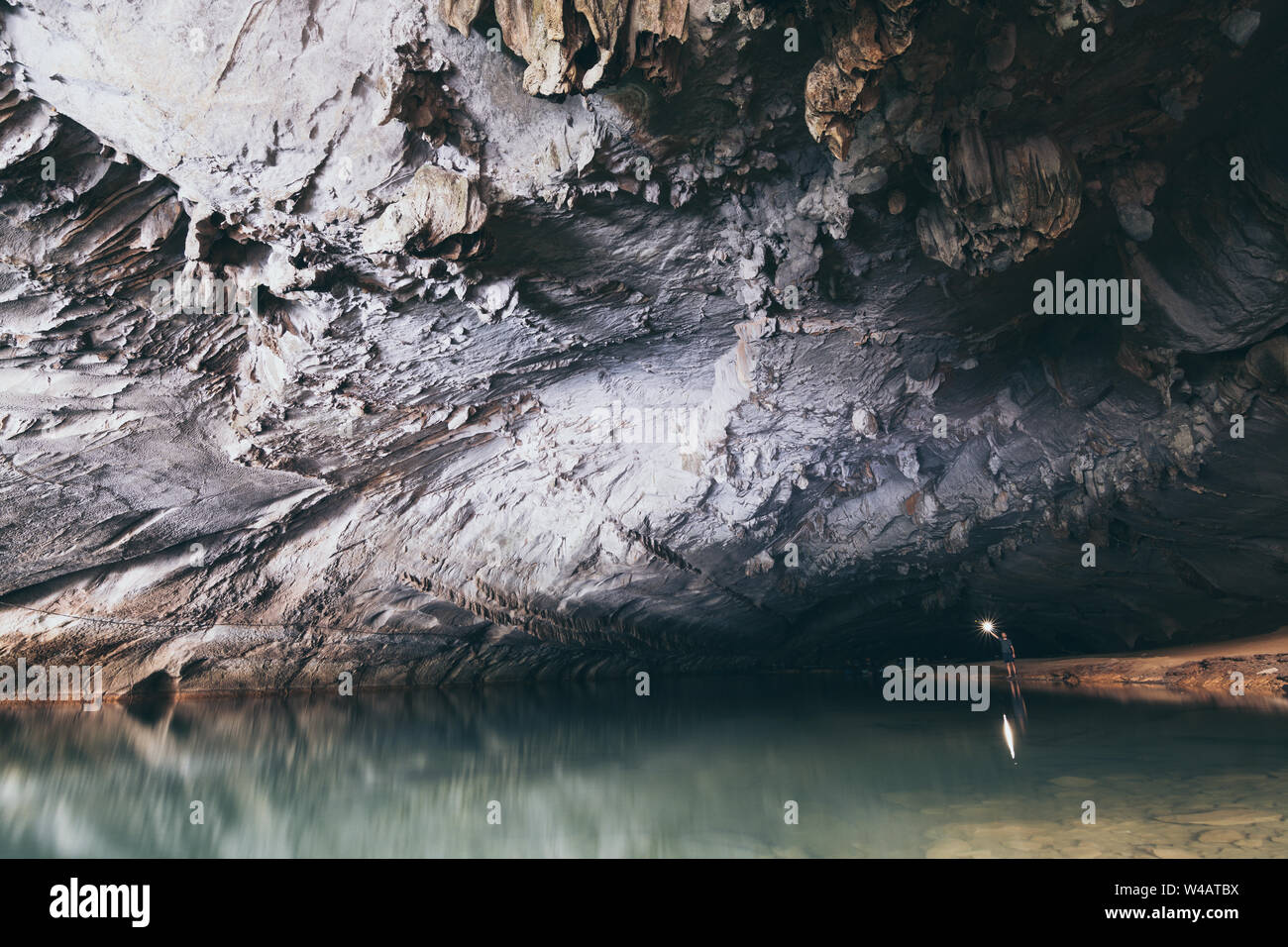 Les droits de l'ossature est à l'intérieur de la grotte de l'eau avec une torche dans la main en Konglor, Laos. Banque D'Images