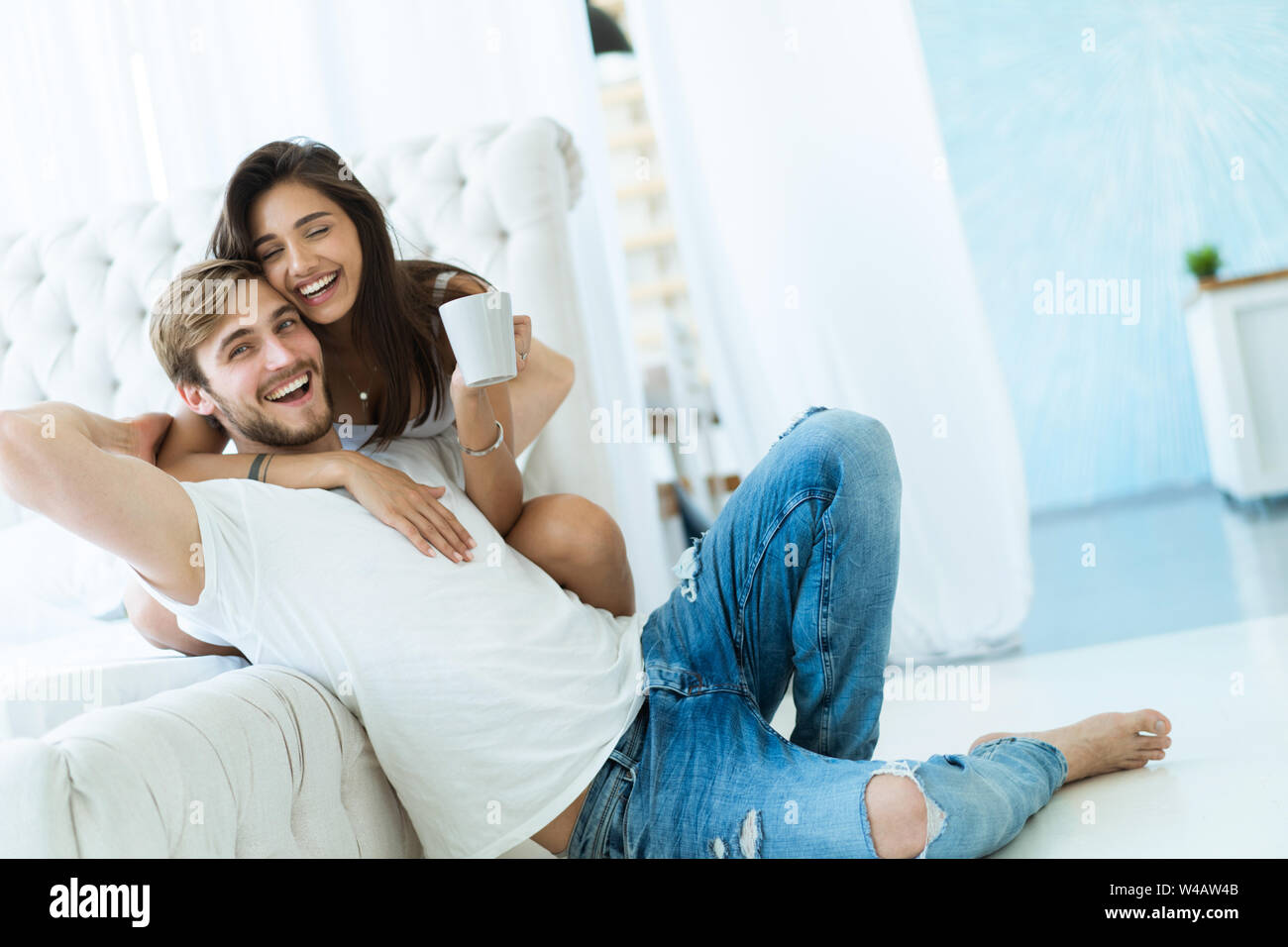 Aimer les jeunes couple hugging and relaxing on sofa à la maison. Banque D'Images