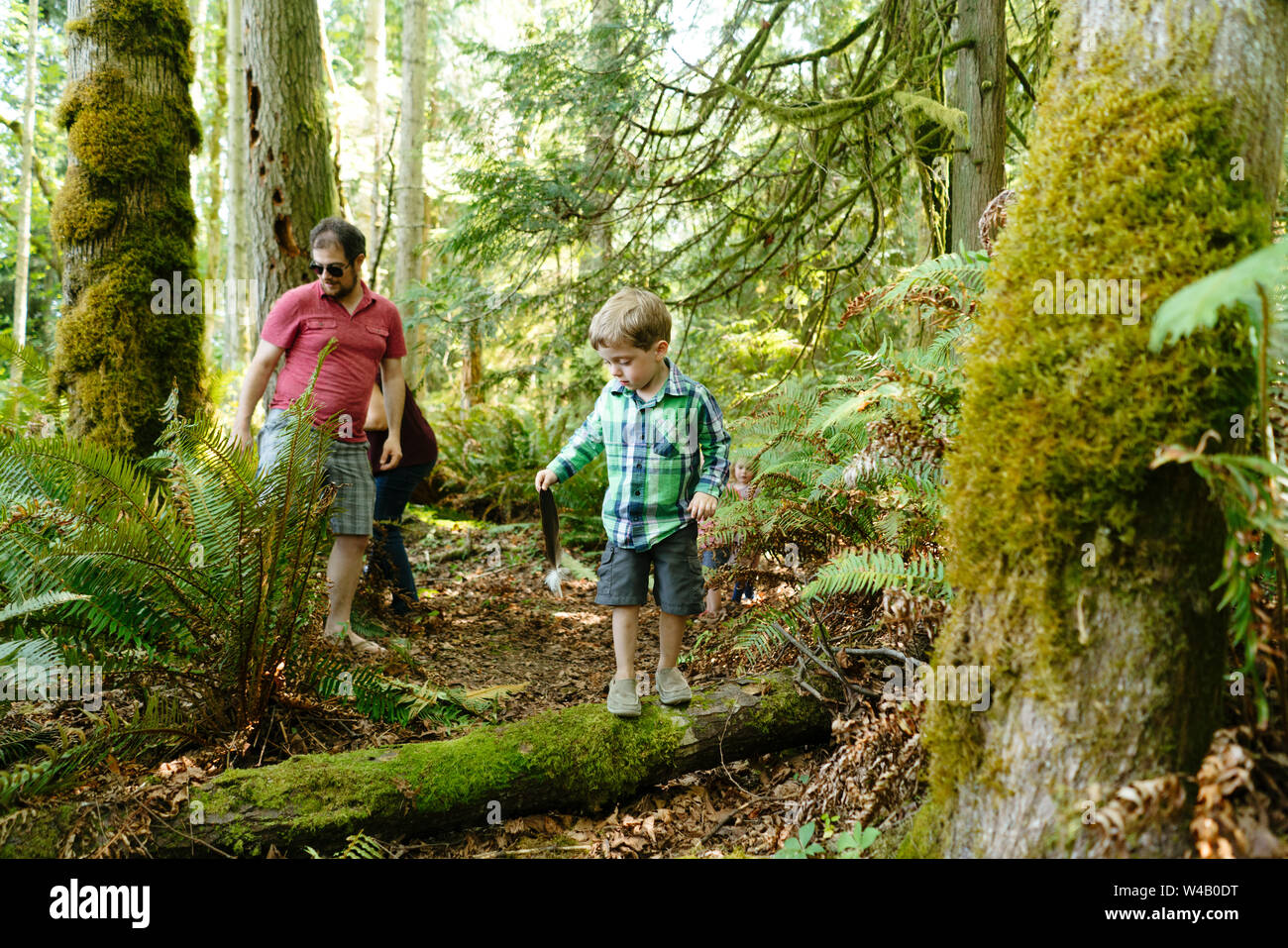Un garçon tenant une plume d'Aigle à tête blanche lors d'une randonnée avec sa famille Banque D'Images