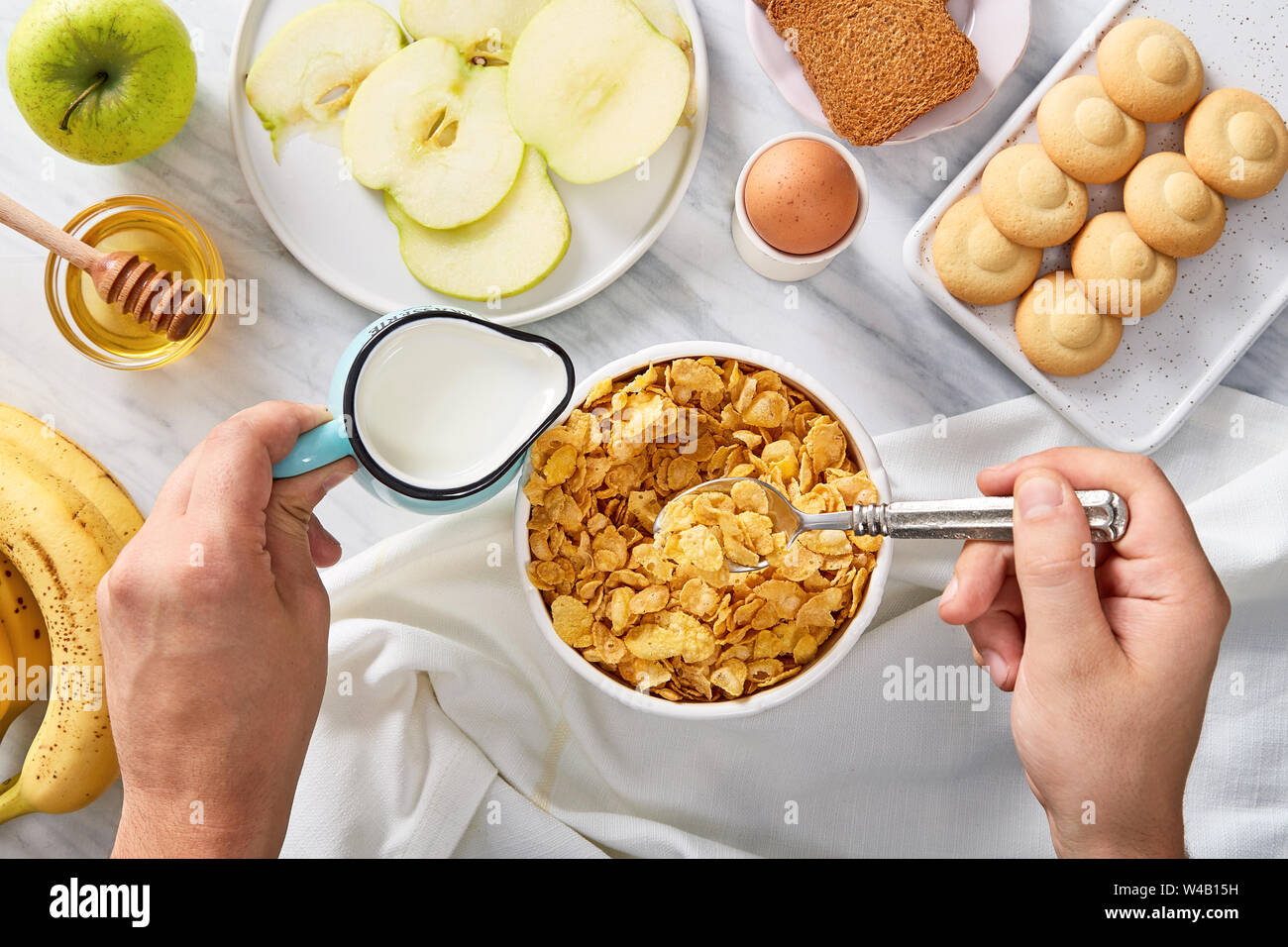 Petit-déjeuner copieux ingrédients. Verser le lait dans les céréales. Vue d'en haut Banque D'Images