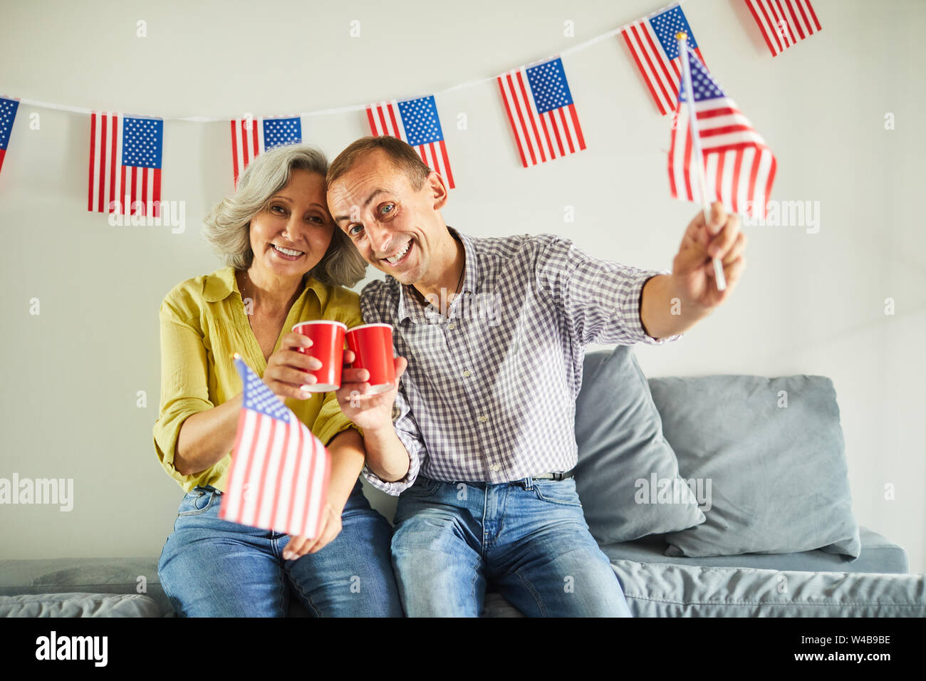Portrait of happy senior couple waving American flag and smiling at camera, copy space Banque D'Images