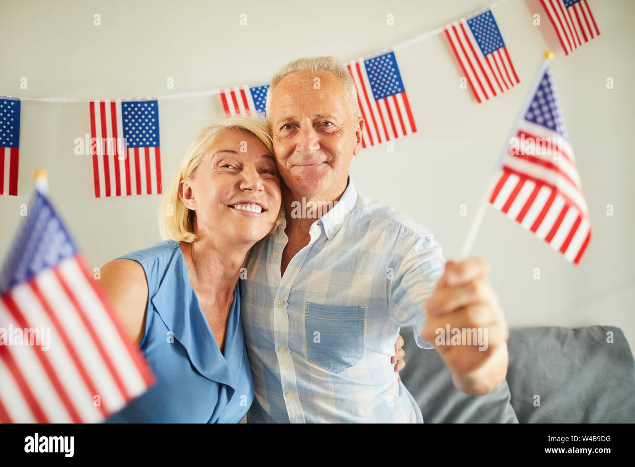Portrait of happy senior couple waving American flag and smiling at camera Banque D'Images