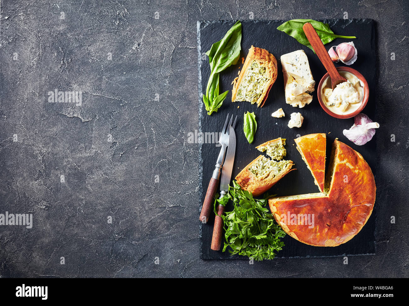 Haricots verts et épinards Tarte au fromage bleu ardoise noire en tranches sur un plateau avec crème au fromage bleu sauce dans un bol sur une table, vue de dessus, copiez Banque D'Images
