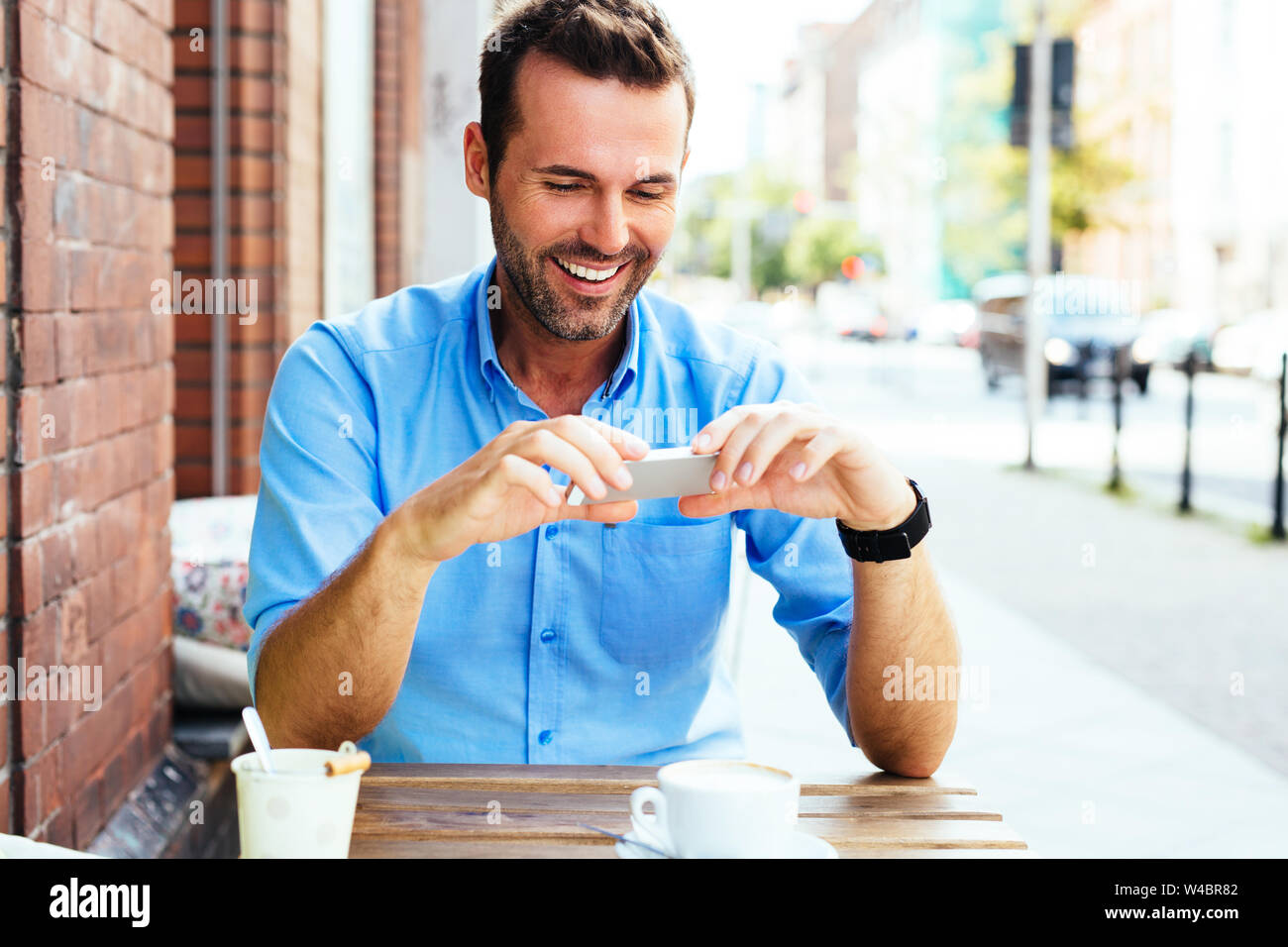 Jeune homme sur internet navigation sur son smartphone dans outdoor cafe Banque D'Images