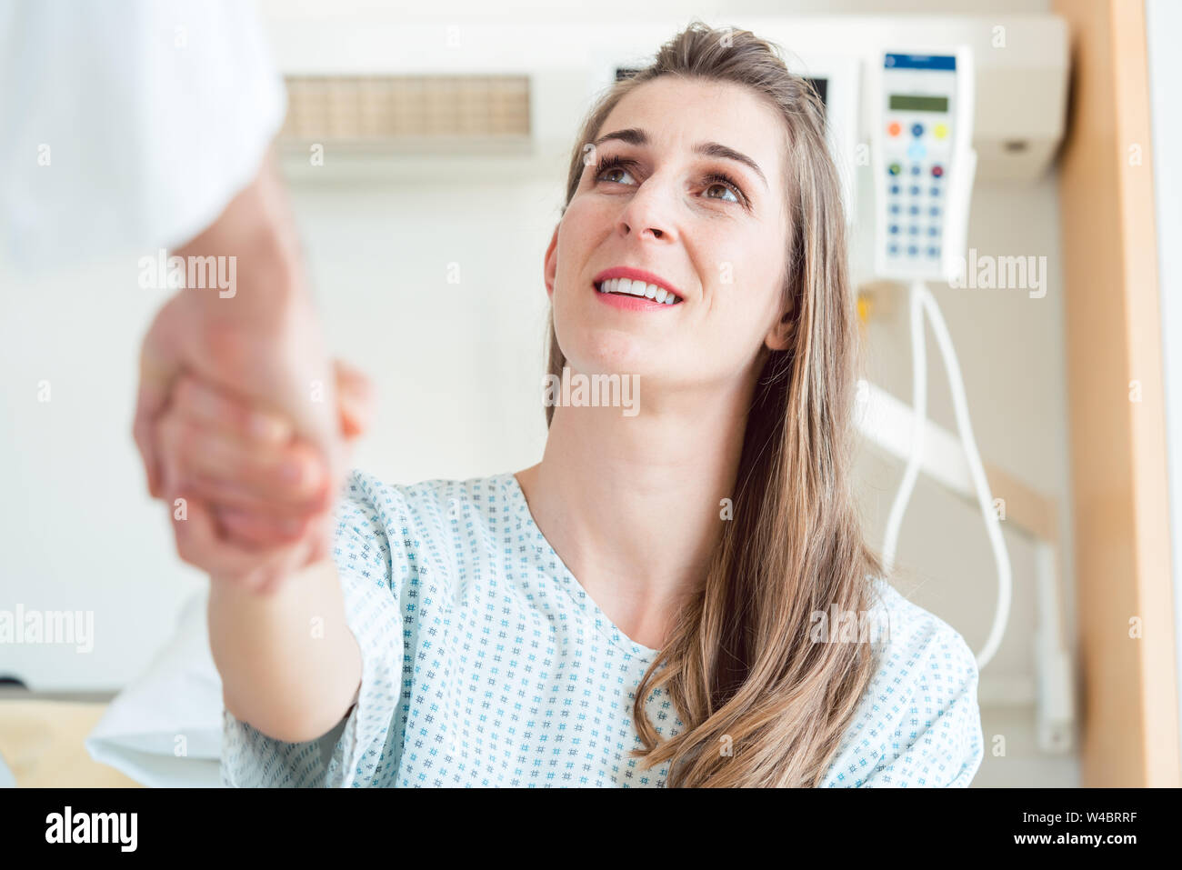 Doctor shaking hand of patient in hospital bed Banque D'Images