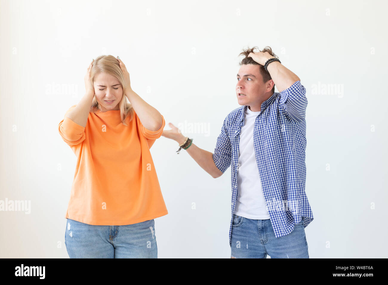 Les jeunes cris guy hipster levant les mains jusqu'à sa chère fille sur un fond blanc. Concept de mauvaises relations et l'éclatement de la famille. Banque D'Images