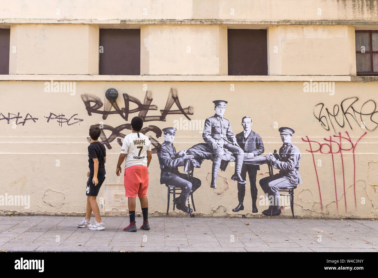 Scène de rue de Paris - deux garçons jouant avec le ballon à côté du street art stencil, 10e arrondissement de Paris, France, Europe. Banque D'Images
