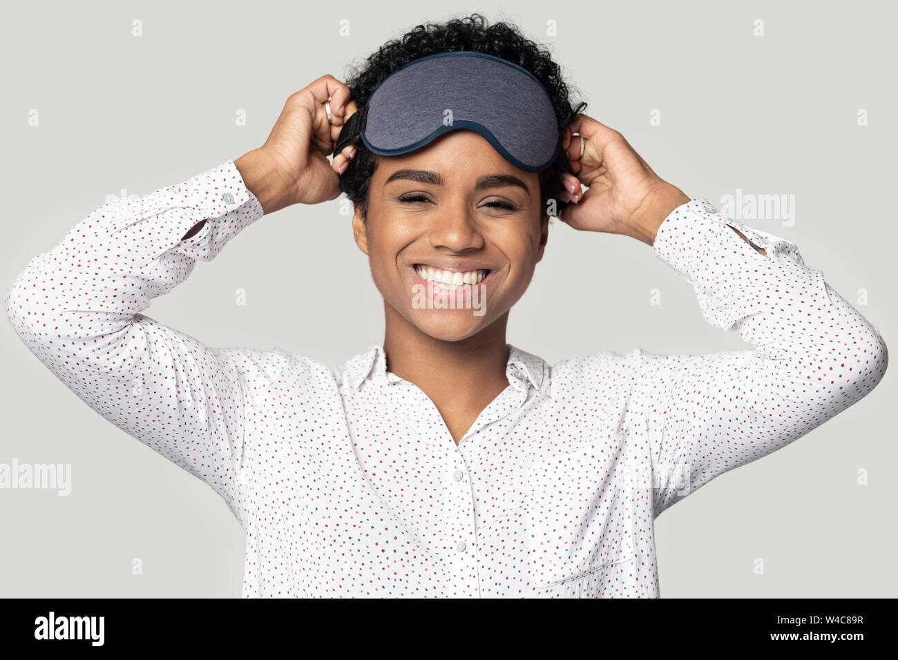Happy black girl rire portant masque de sommeil gris sur la tête Banque D'Images
