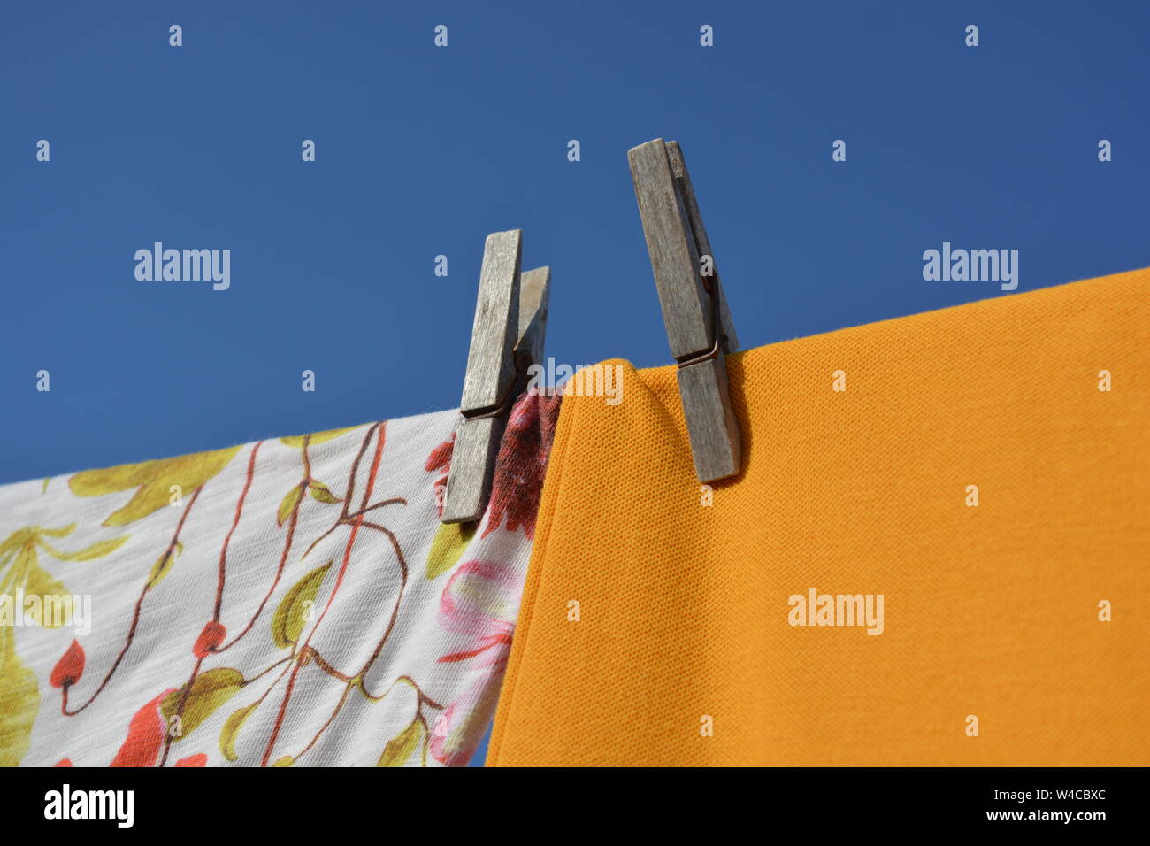 Blanchisserie en train de sécher dehors en plein air sur une chaude journée ensoleillée,. Close up, détail des chemises colorées et des pinces contre fond de ciel bleu avec l'exemplaire sp Banque D'Images