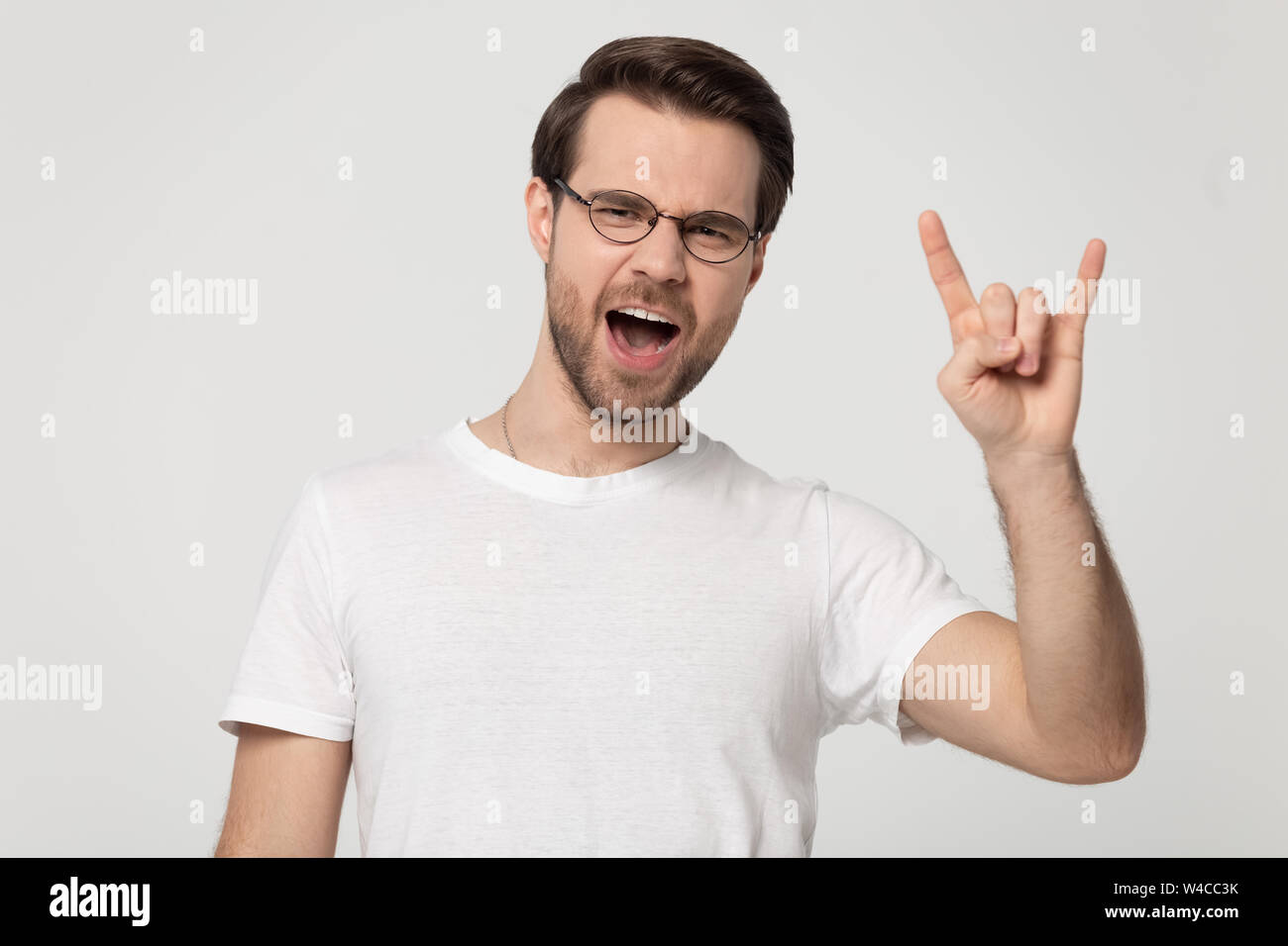 En montrant l'homme millénaire lunettes rock and roll hand gesture Banque D'Images