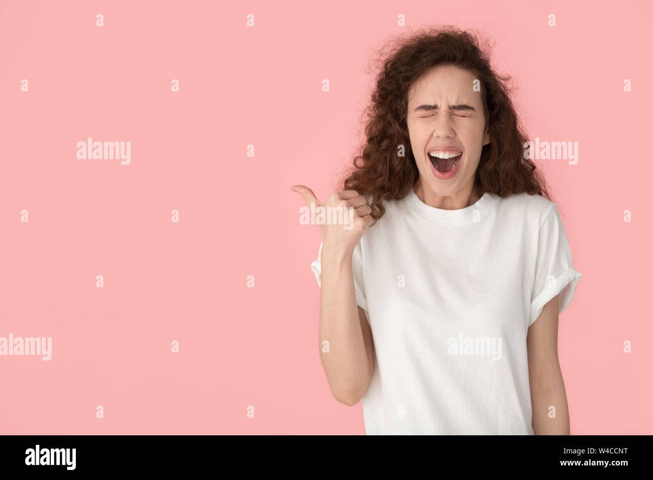 Cheerful brown-haired woman laughing doigt de côté à copyspace Banque D'Images