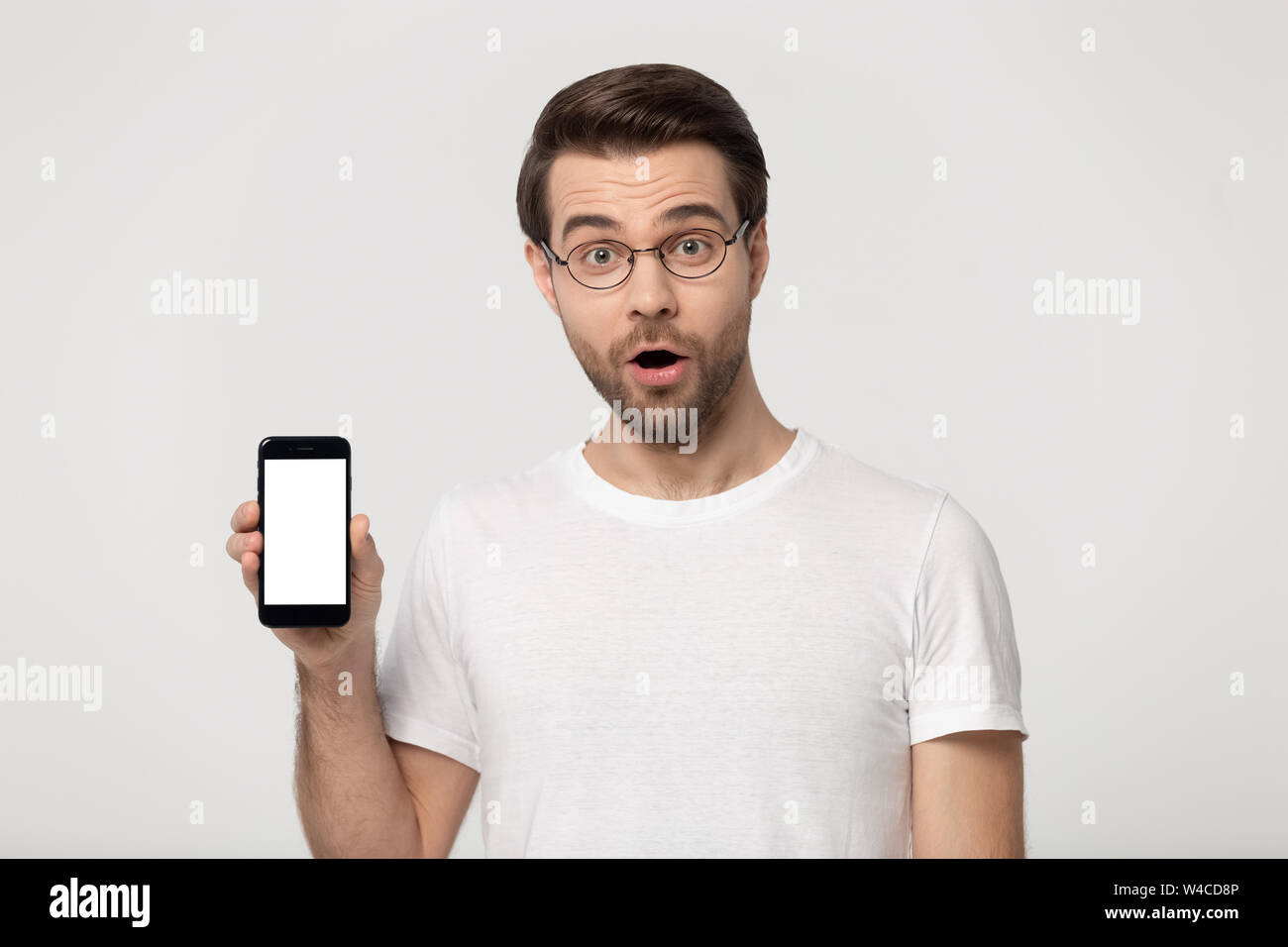 Surpris man show smartphone avec maquette vierge écran studio shot Banque D'Images