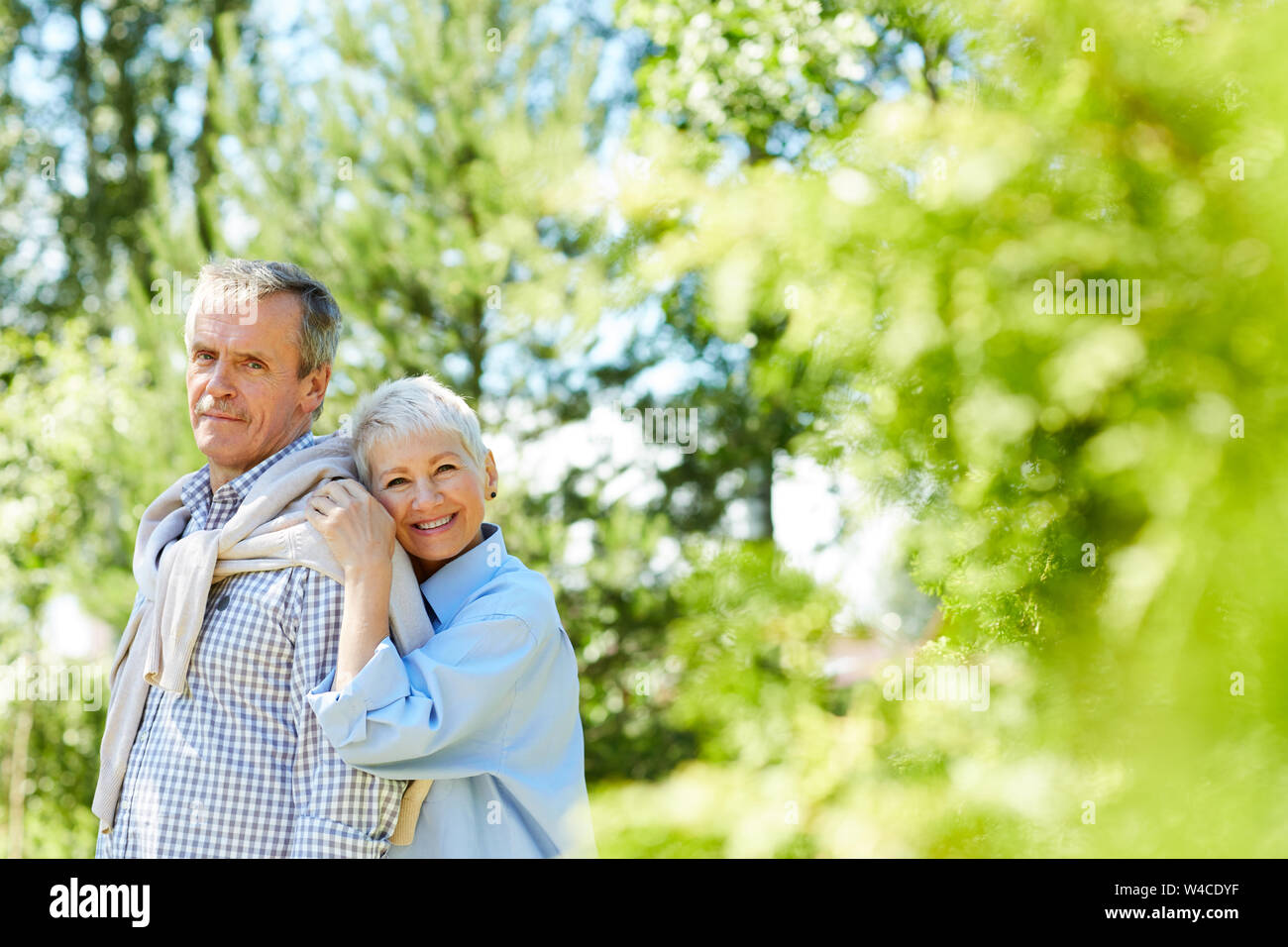 Portrait of senior woman leaning on son mari pendant la prise de portrait de famille à l'extérieur, copy space Banque D'Images
