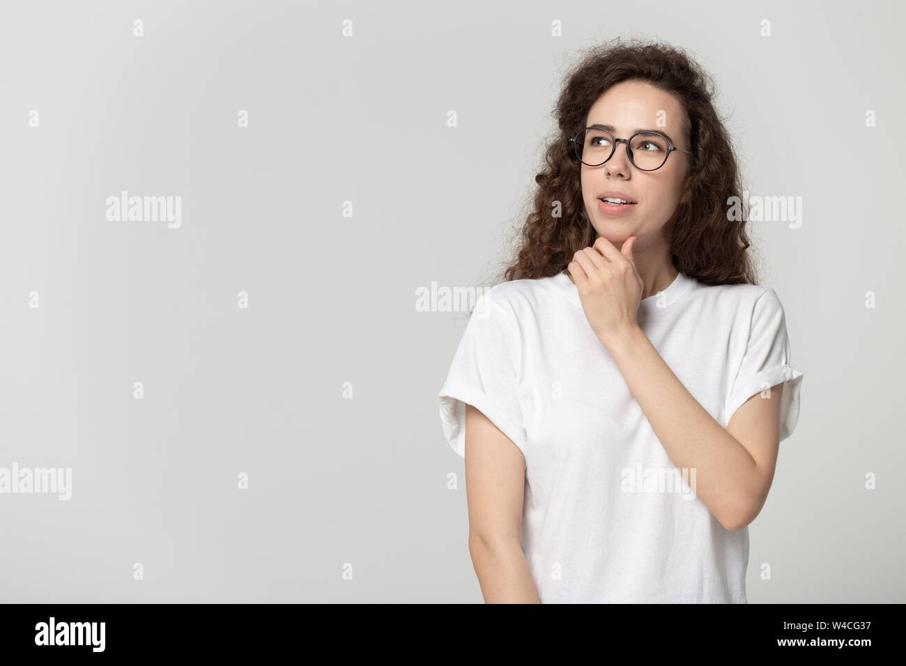 Jolie femme à lunettes penser posant isolé sur fond gris Banque D'Images