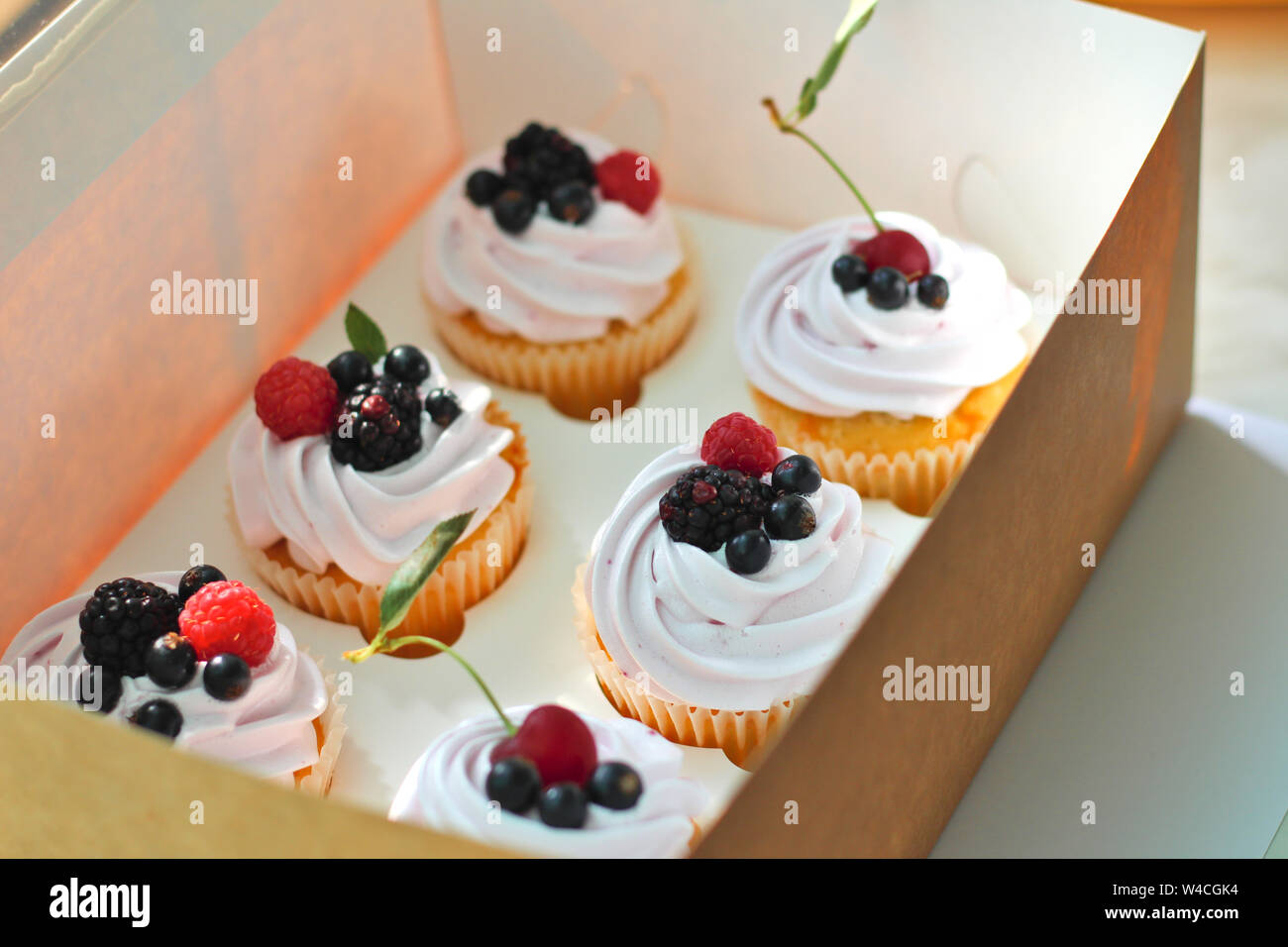 Cupcakes isolés avec de la crème, avec une feuille de cerise, de mûre, de framboise cassis dans un ouvrage fort sur un fond blanc. Banque D'Images