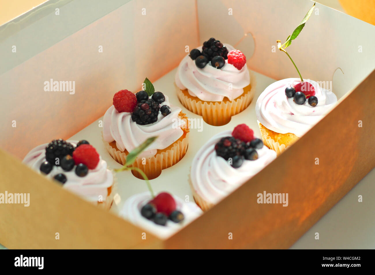Cupcakes isolés avec de la crème, avec une feuille de cerise, de mûre, de framboise cassis dans un ouvrage fort sur un fond blanc. Banque D'Images