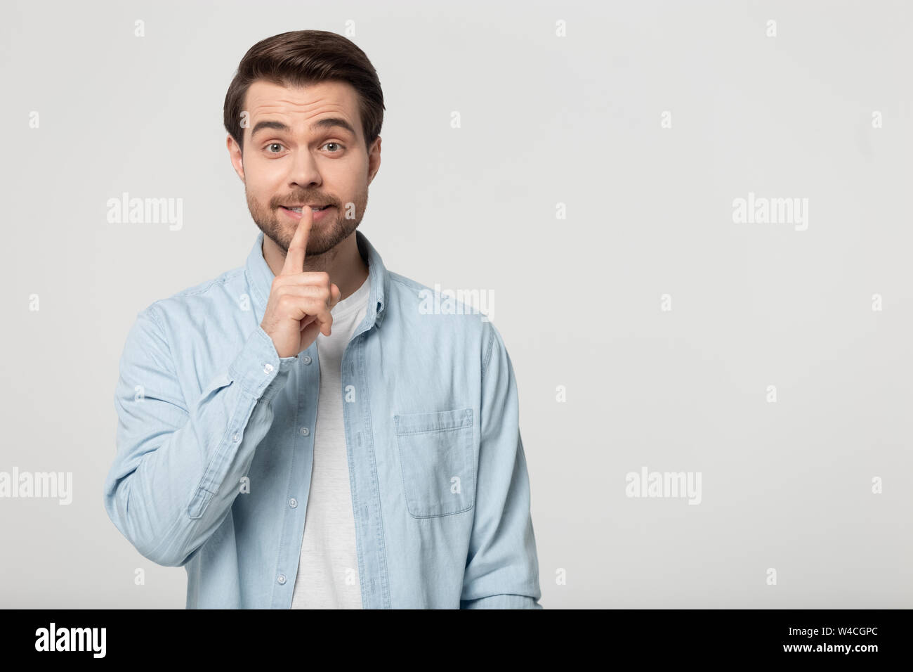 L'homme détient doigt sur lèvres fait geste hush studio shot Banque D'Images