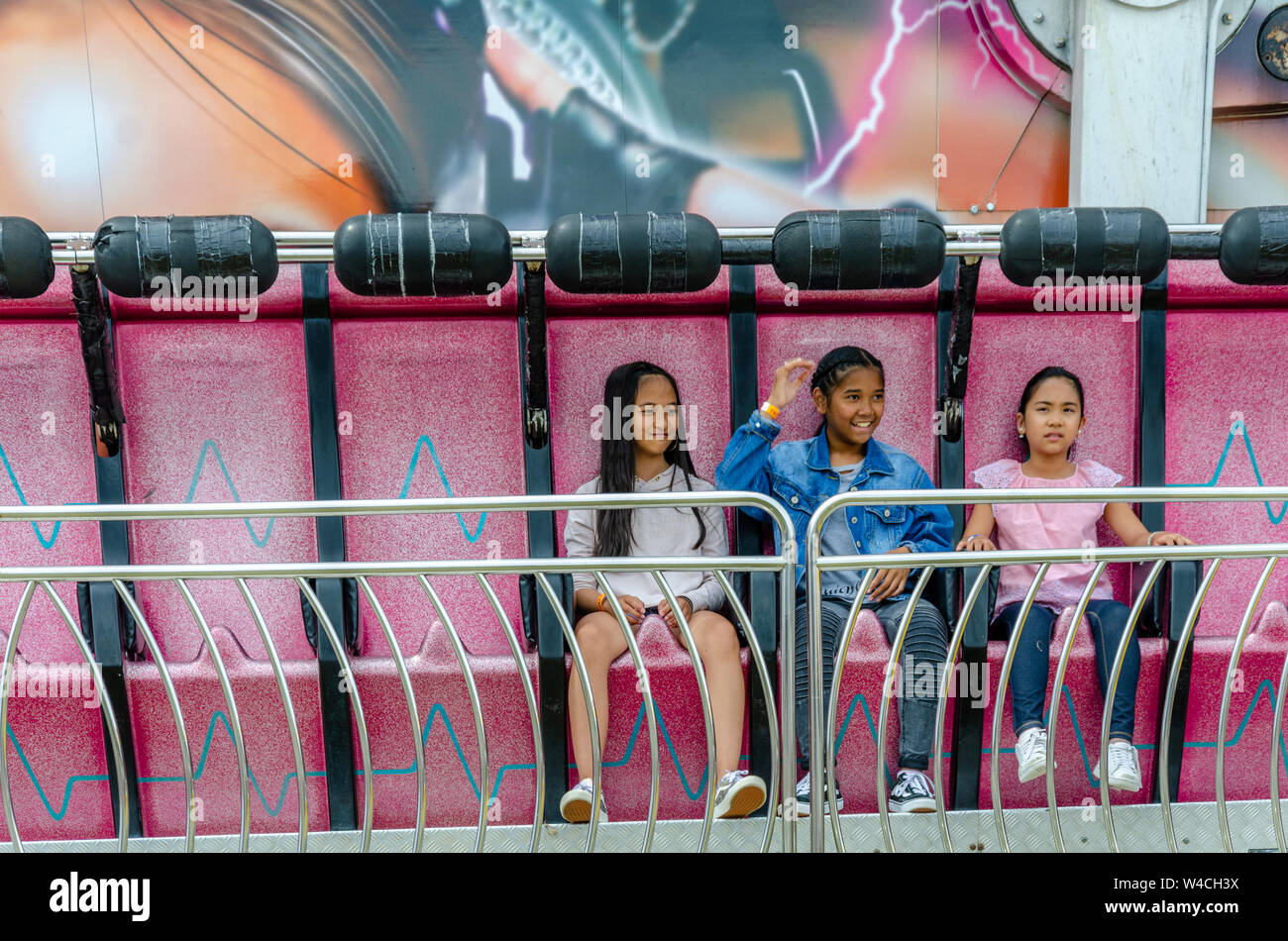 Trois jeunes filles monter seul sur une attraction pour un juste motif. Banque D'Images