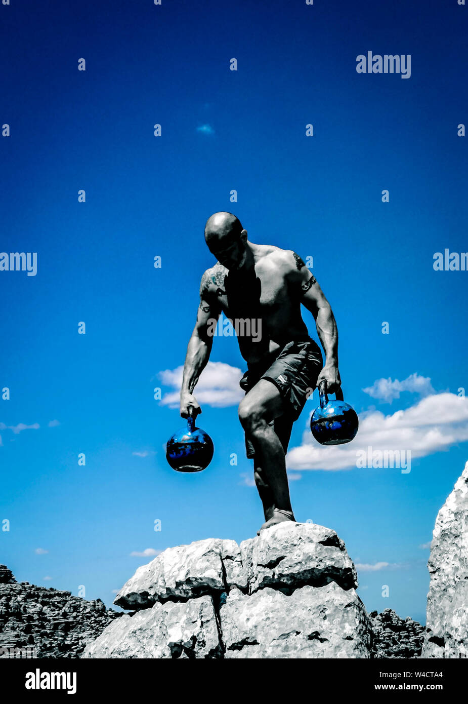 Homme marchant sur un rocher portant deux Kettlebells Banque D'Images