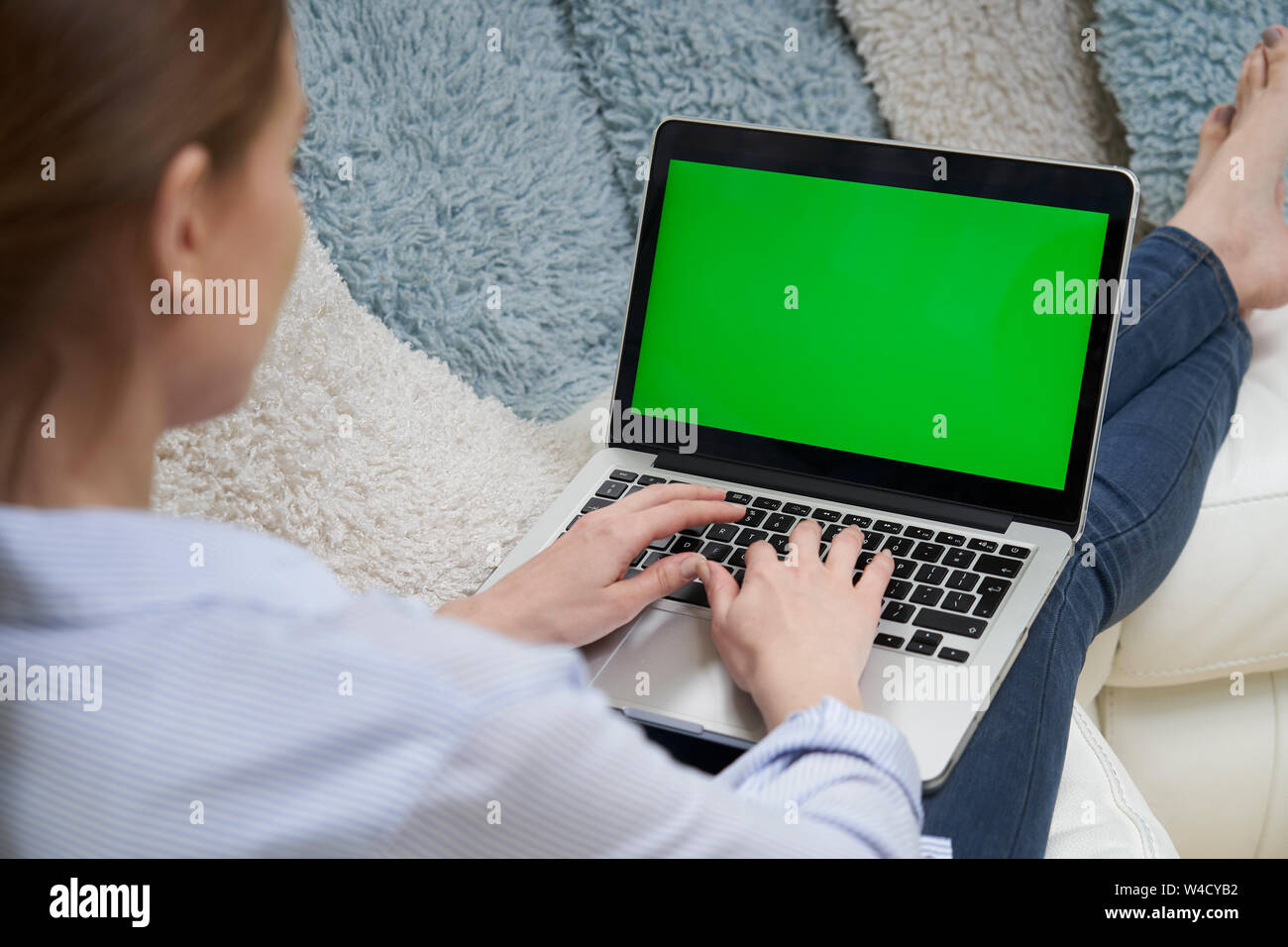 Au cours de l'épaule de Woman Lying On Sofa Using laptop écran vert Banque D'Images