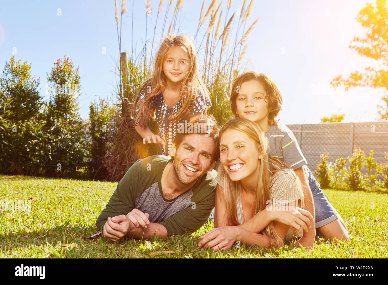 Famille heureuse avec deux enfants se trouve dans le jardin en été sur la pelouse Banque D'Images