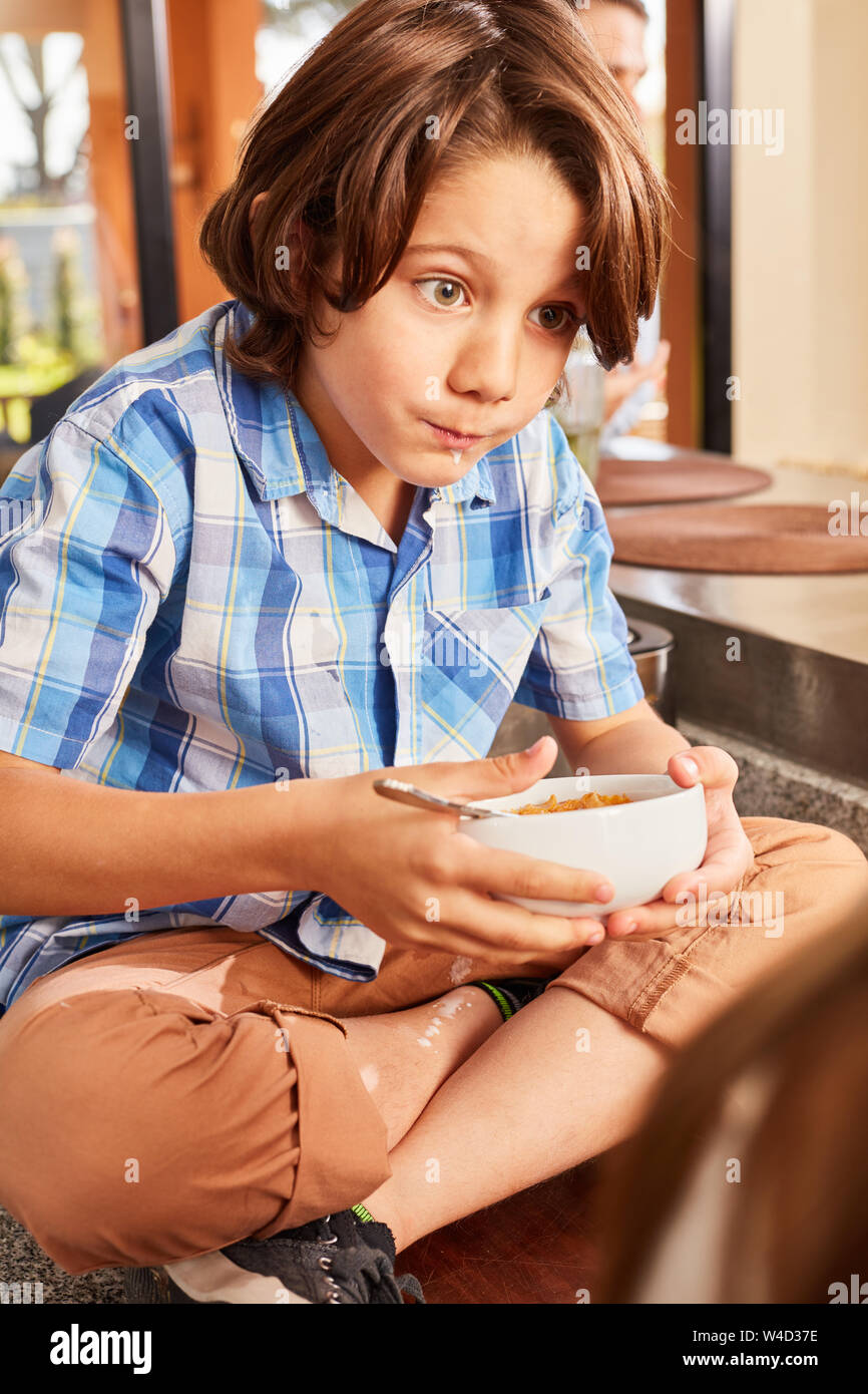 Le garçon à la faim manger des céréales le matin dans la cuisine comme d'un petit-déjeuner sain Banque D'Images