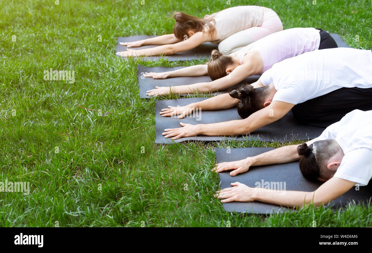 Groupe de gens allongés sur des tapis de yoga de faire poser l'enfant Banque D'Images