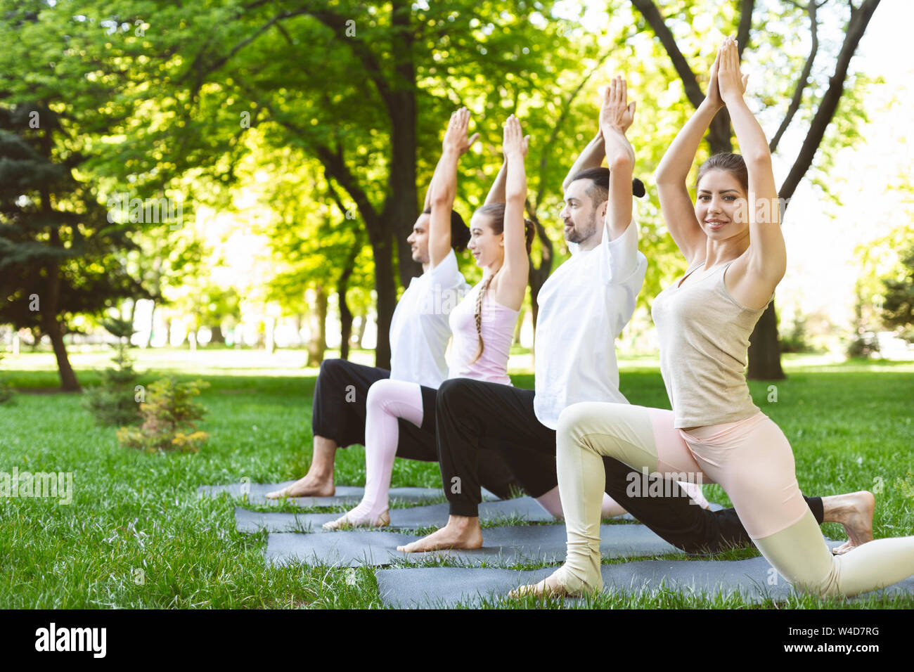 Groupe qui se posent à l'extérieur en yoga warrior Banque D'Images