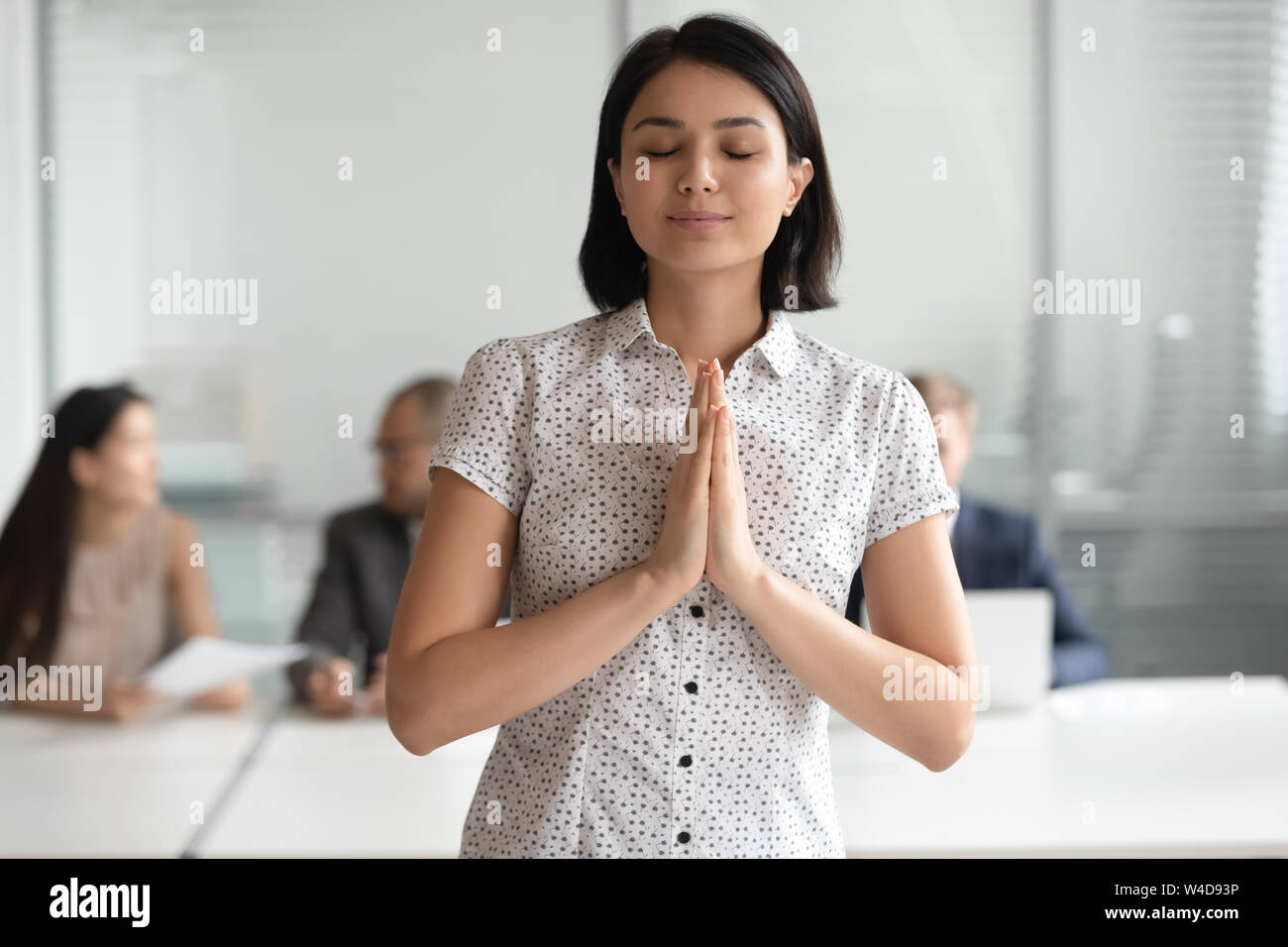 Reconnaissant asian businesswoman meditating prier avec espoir standing in office Banque D'Images