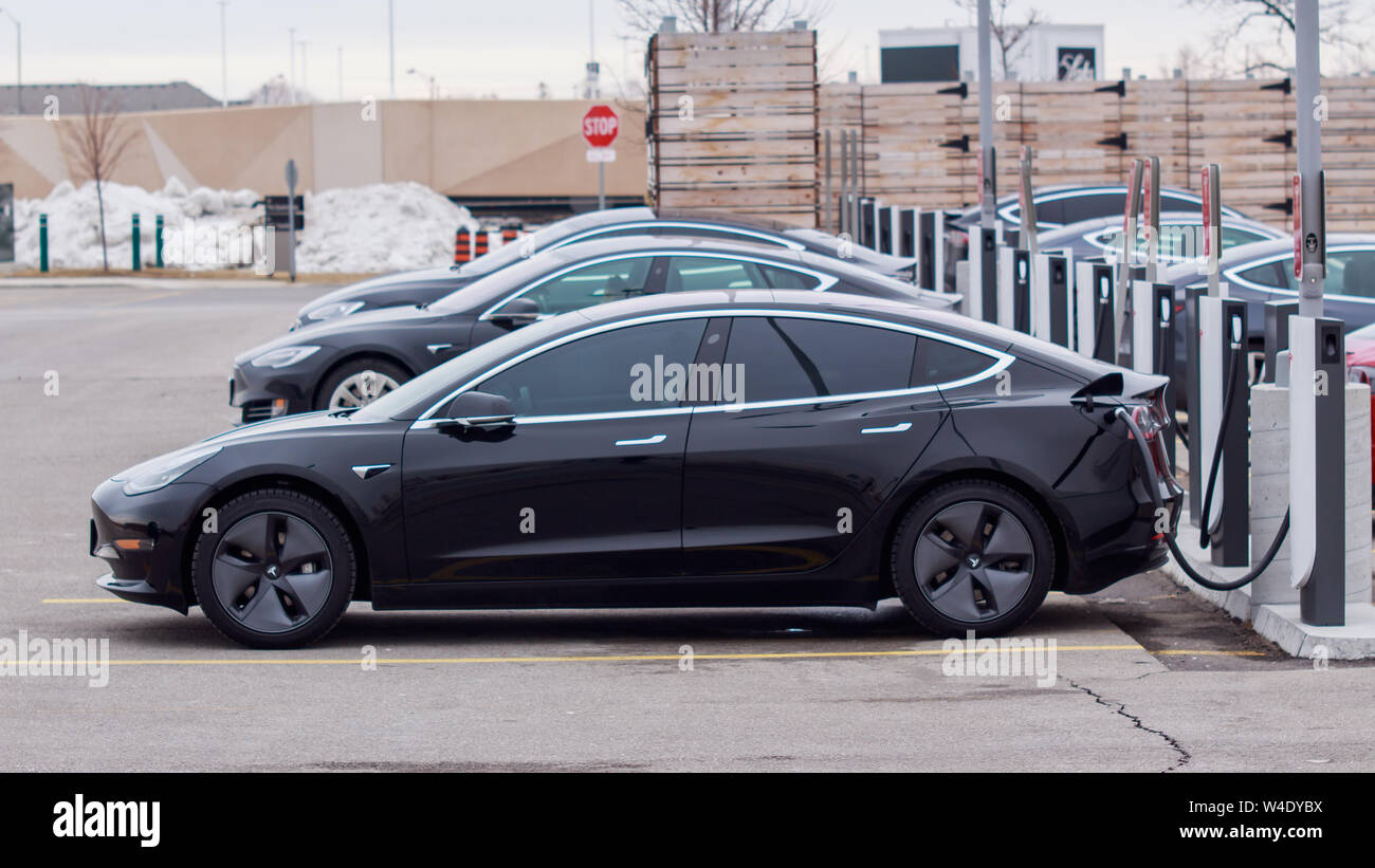 Modèle Tesla 3 garé branché à un compresseur Tesla avec d'autres véhicules à CF Sherway Gardens, Toronto (Etobicoke). Banque D'Images