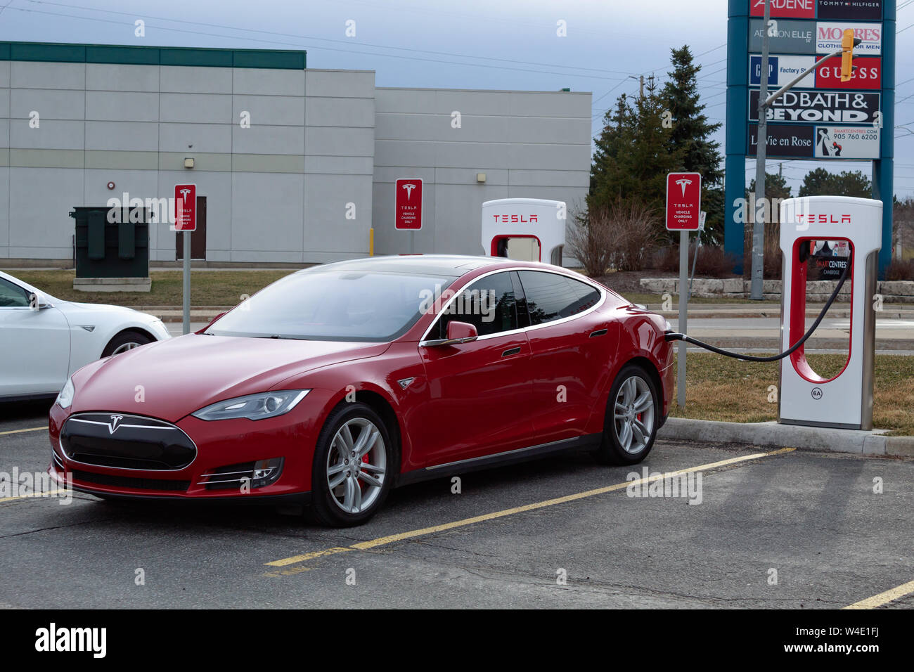 Tesla Model S rouge suralimenter chez Tesla Supercharger, Cambridge smartcentres emplacement. Banque D'Images