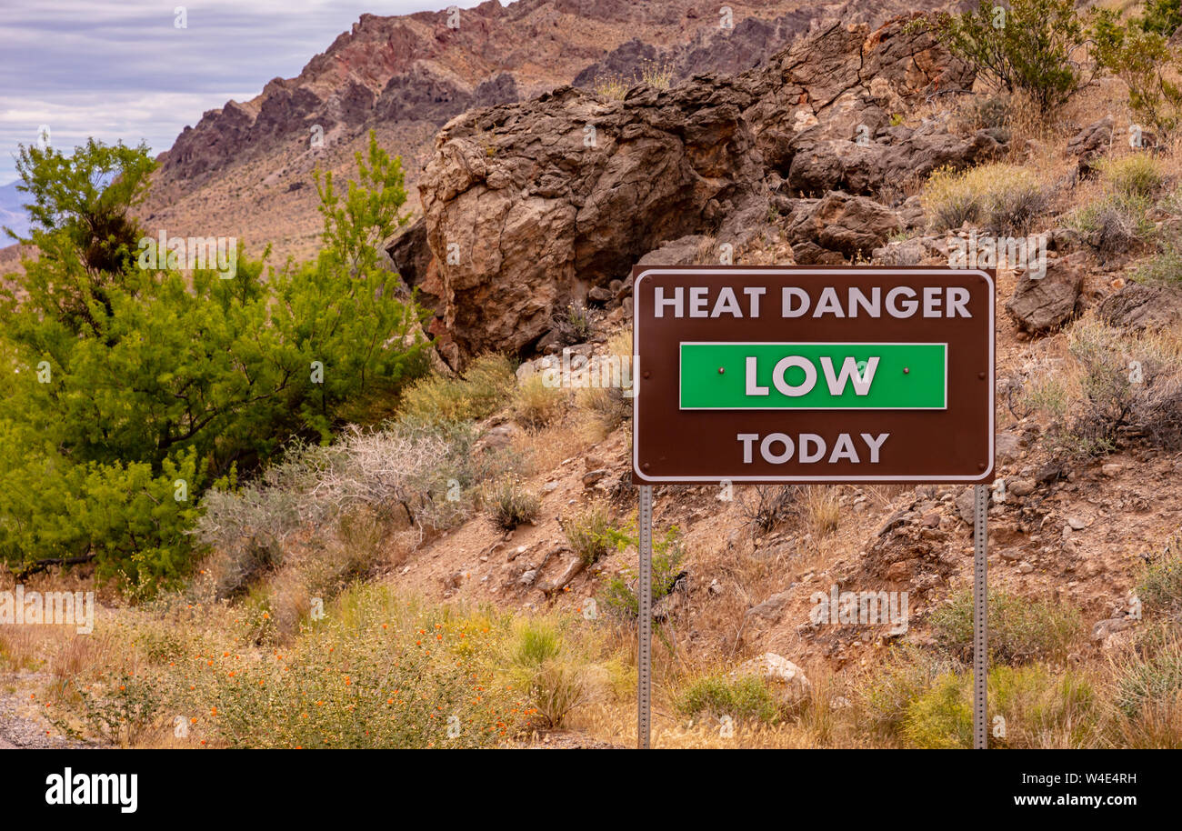Vallée de Feu park, NEVADA USA. Panneau d'avertissement de chaleur Chaleur texte faible danger aujourd'hui. Des formations de roche de grès rouge et bleu ciel avec nuages de fond Banque D'Images