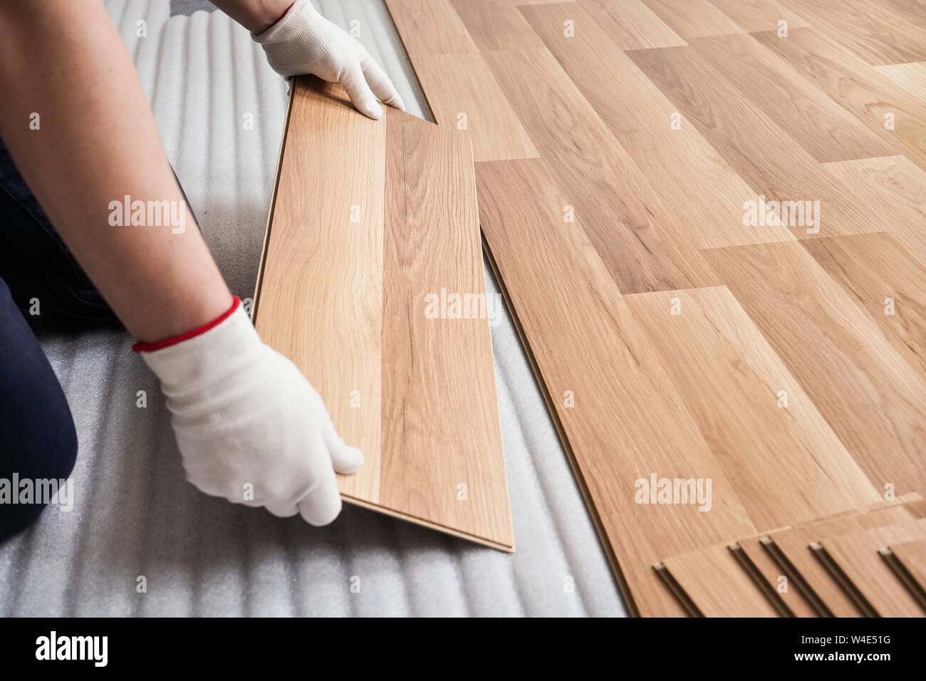 L'installation de plancher laminé, détail sur l'homme les mains avec des  gants blancs en bois raccord tuile, plus de mousse blanche couche de base  Photo Stock - Alamy