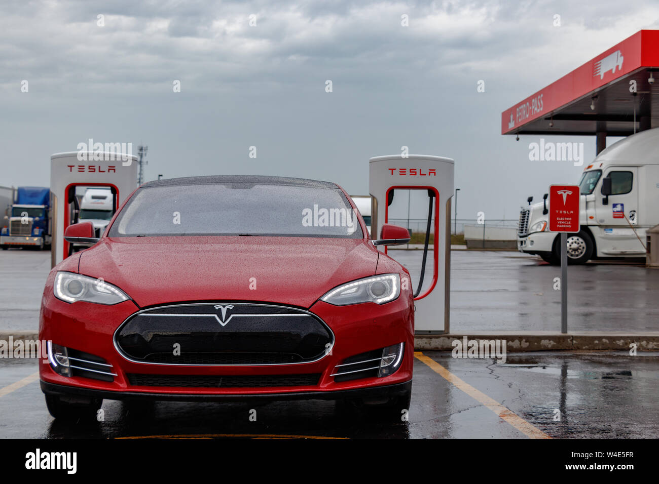 Avant de Tesla Tesla Model S à la station de compresseur sous la pluie, avec l'arrêt de camion vu derrière. Banque D'Images