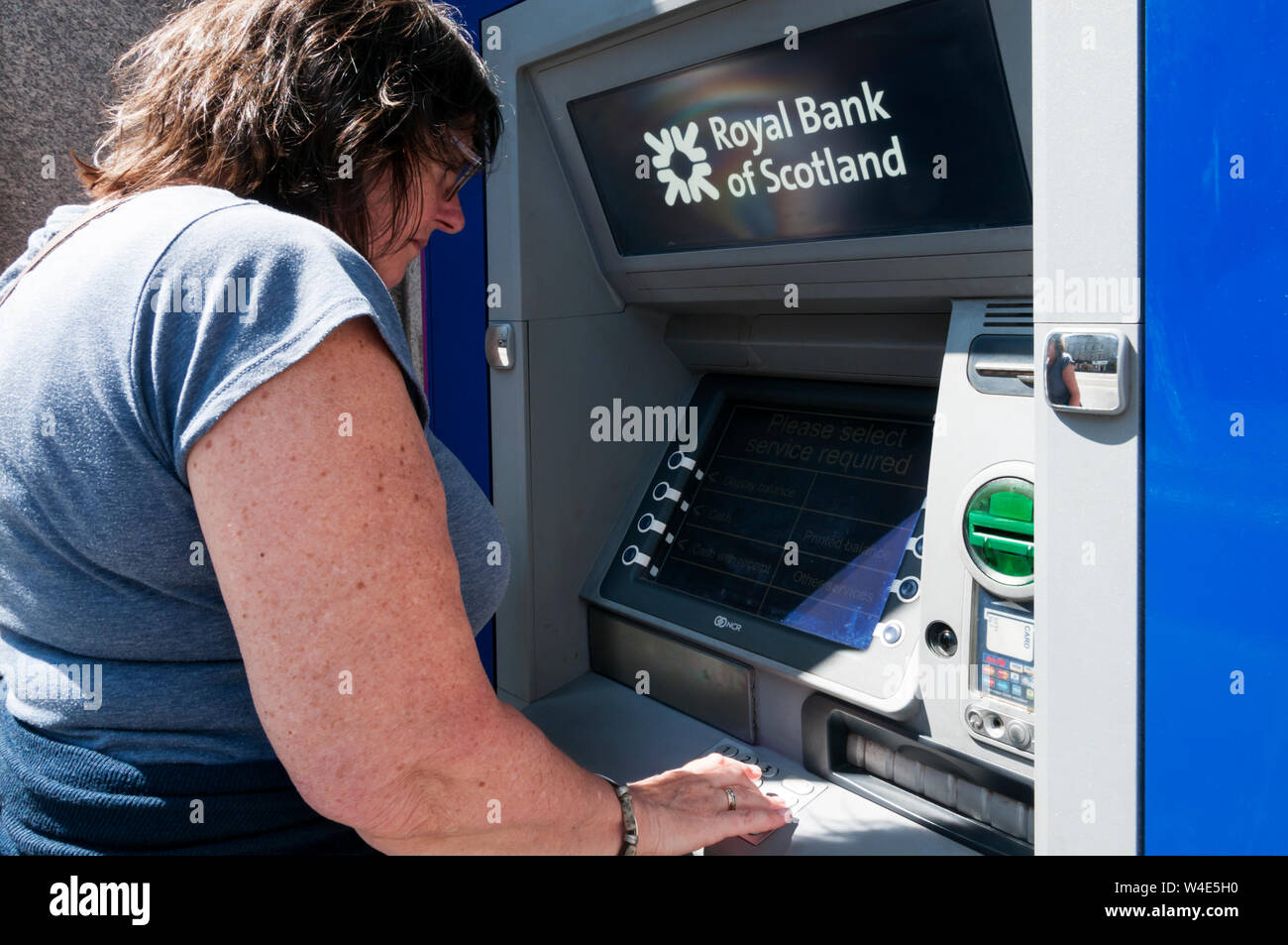Une femme à l'aide d'un Royal Bank of Scotland cash machine. Banque D'Images