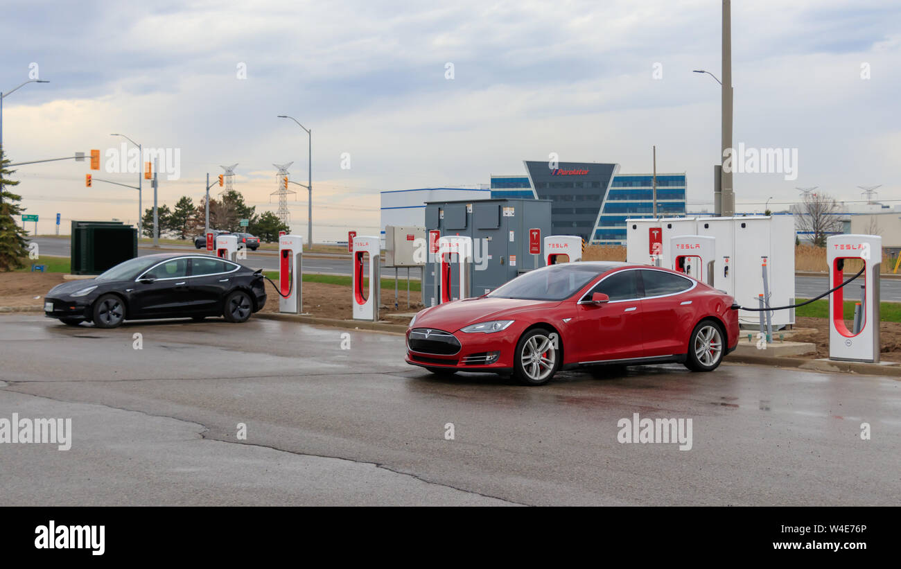 Tesla Model S rouge et noir modèle Tesla 3 branché en charge, chez Tesla Supercharger Gare à Mississauga, en Ontario. Banque D'Images