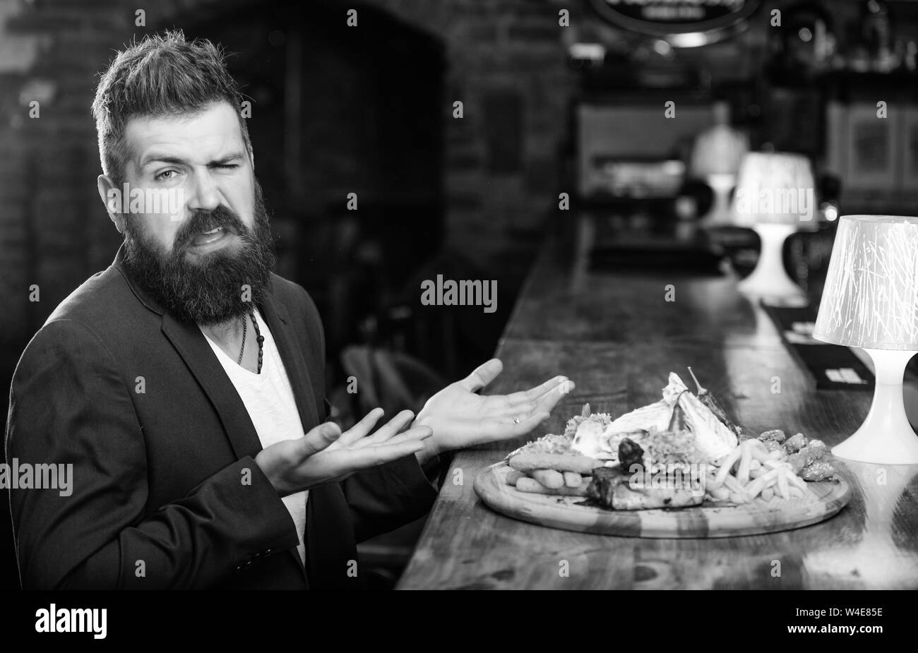L'homme a reçu de pommes de terre frites repas avec les bâtonnets de poisson viande. Délicieux repas. Profitez de repas. Tricher repas. Hipster faim manger pub aliments frits. Restaurant client. Costume officiel Hipster s'asseoir au comptoir du bar. Banque D'Images