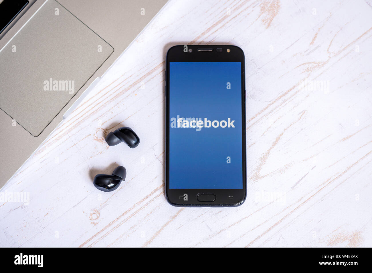 Nizhyn, Ukraine/Juillet-16-2019 : Smarthone avec application Facebook et écouteurs allongé sur la table. Concept des médias sociaux Banque D'Images