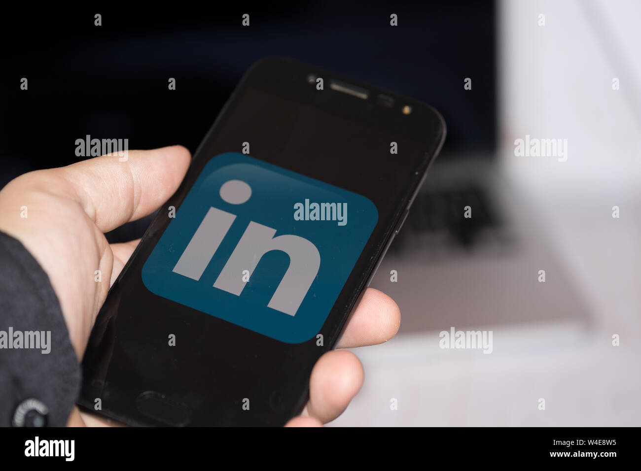 Nizhyn, Ukraine/Juillet-16-2019 : jeune représentant l'homme en noir de tenir téléphone et d'utiliser Linkedin app. Les médias sociaux et corporatifs concept. Banque D'Images