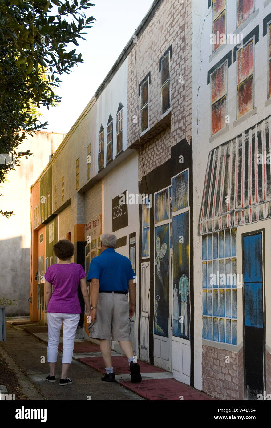 Couple de personnes âgées caucasiennes (60 à 70 ans) marchant sur le trottoir avec une peinture murale peinte sur le mur à Georgetown SC, États-Unis. Banque D'Images