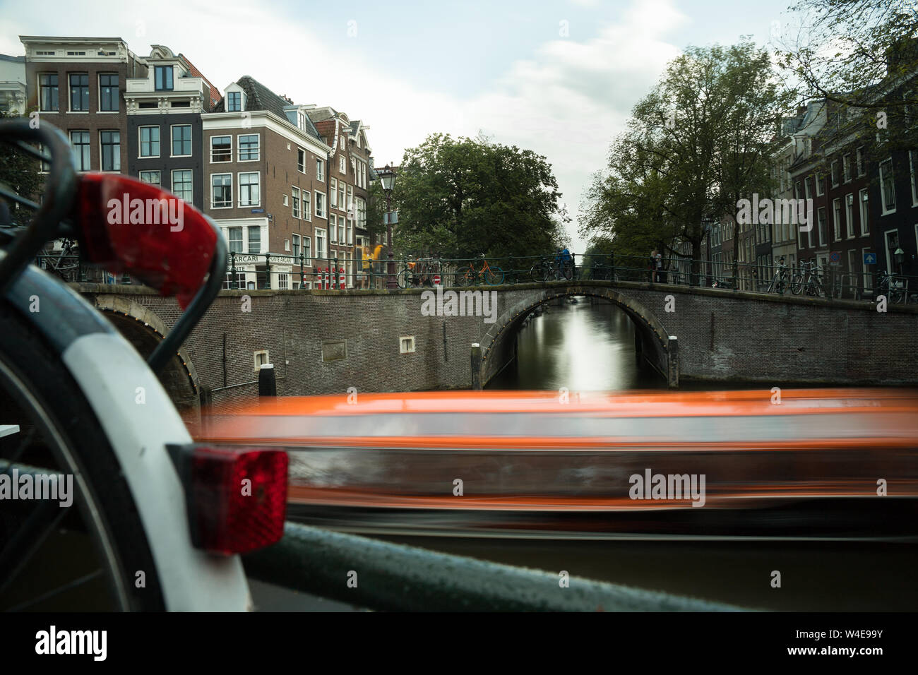 Vélo hollandais le long d'un pont de canal, bateau exposé de longue durée passant par en arrière-plan Banque D'Images