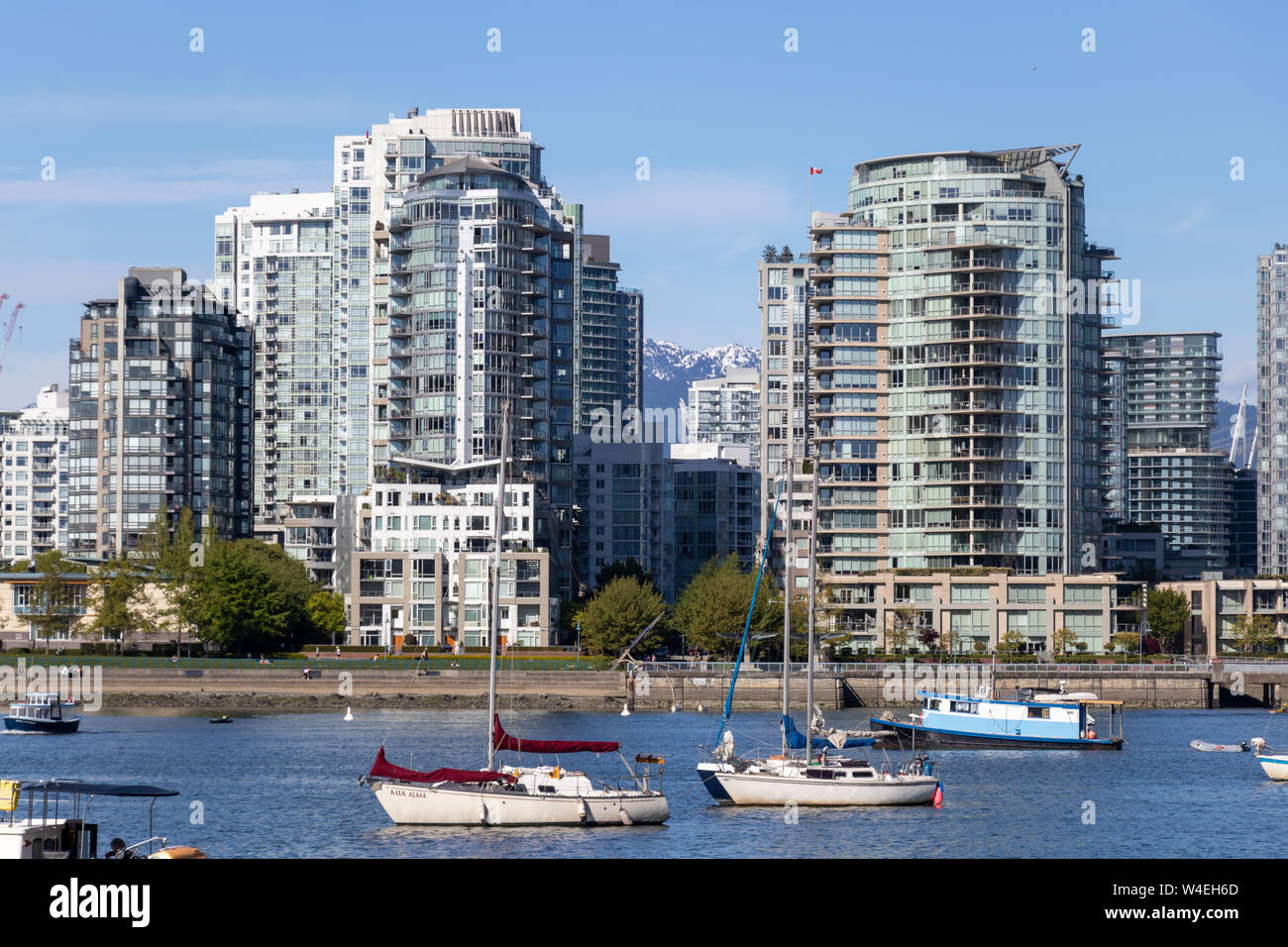 Bateaux dans le port de Vancouver, False Creek avec des condos et des montagnes enneigées en arrière-plan. Banque D'Images
