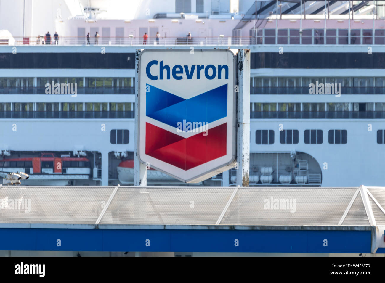 Le logo Chevron Corporation est visible au sommet de sa gare dans le port de Vancouver avec un bateau de croisière amarré en arrière-plan. Banque D'Images
