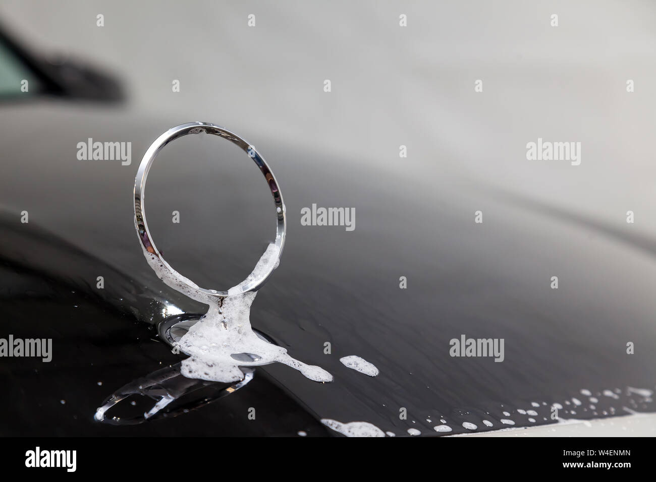 Gros plan sur l'emblème d'un ca sur le capot d'une voiture noire pendant le lavage et le nettoyage dans le détail atelier avec de l'eau et du savon en mousse Banque D'Images