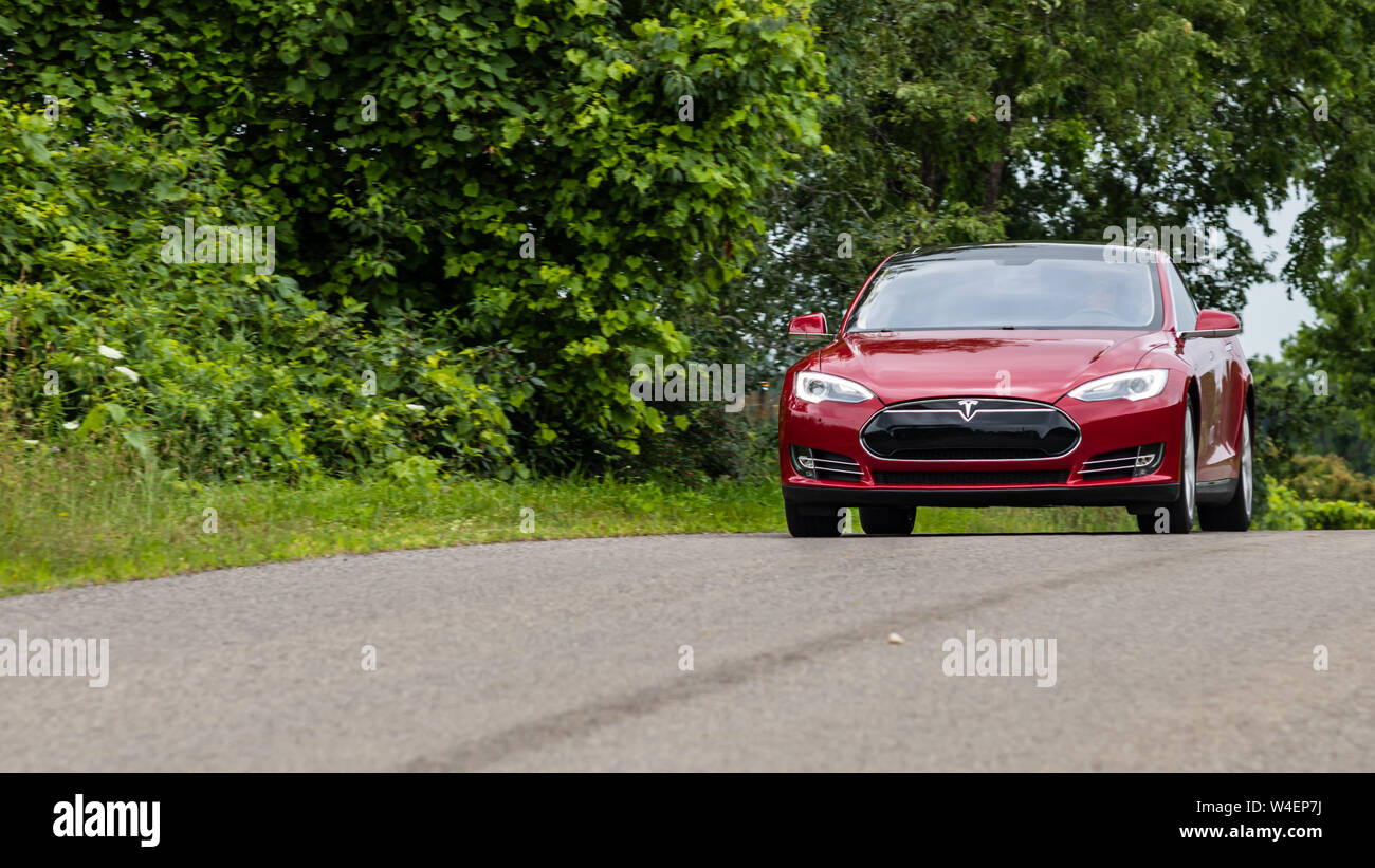 Tesla Model S rouge vu conduire sur une route. Banque D'Images