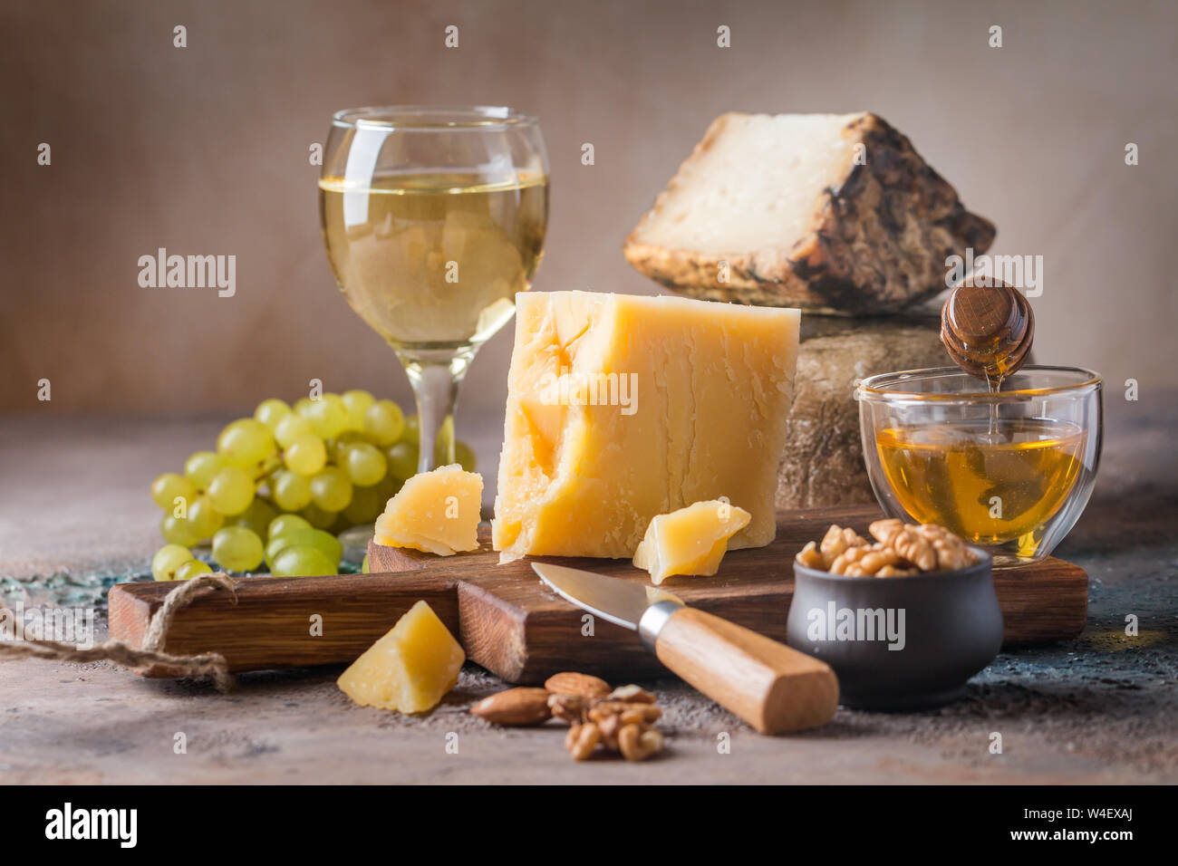Différents types de fromage avec du miel, des raisins et du vin sur fond rustique Banque D'Images