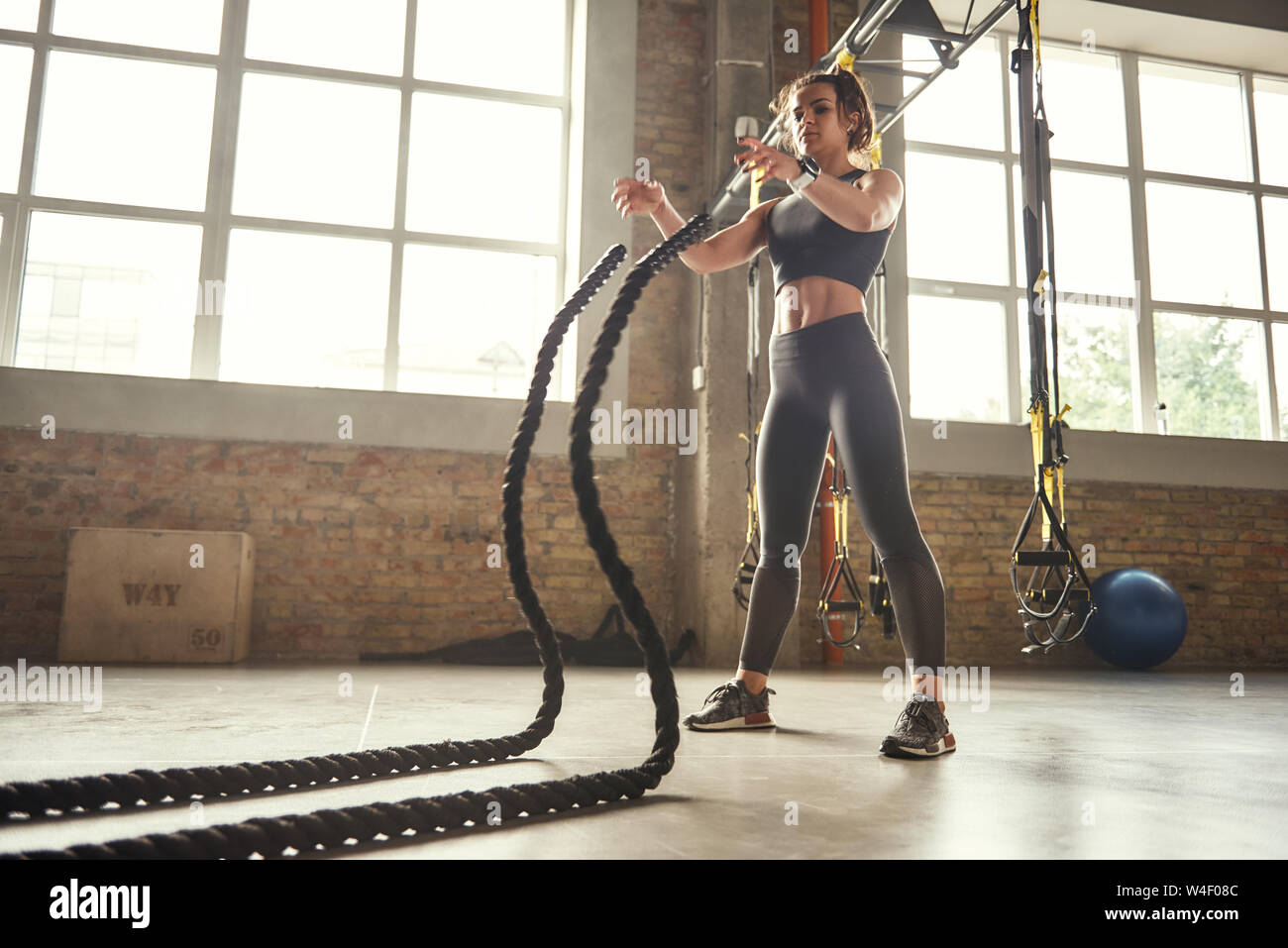 L'entraînement fonctionnel. Jeune femme athlétique avec corps parfait faisant des exercices crossfit avec une corde dans la salle de sport. Concept CrossFit. D'entraînement. Concept d'exercices Banque D'Images