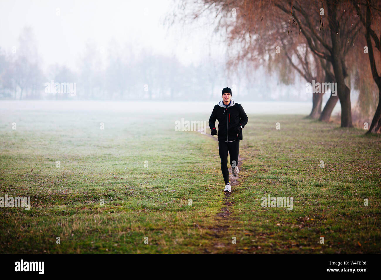 Homme qui court pendant temps de brouillard à l'hiver ou matin d'automne. Banque D'Images
