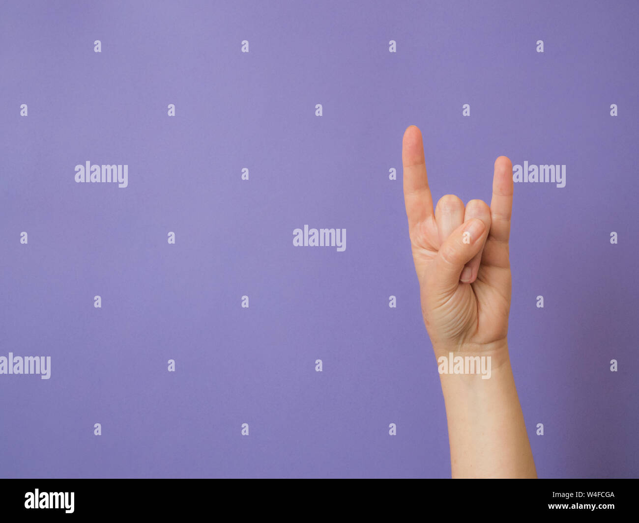 La main féminine montre des signes 'Devil' sur fond violet with copy space Banque D'Images