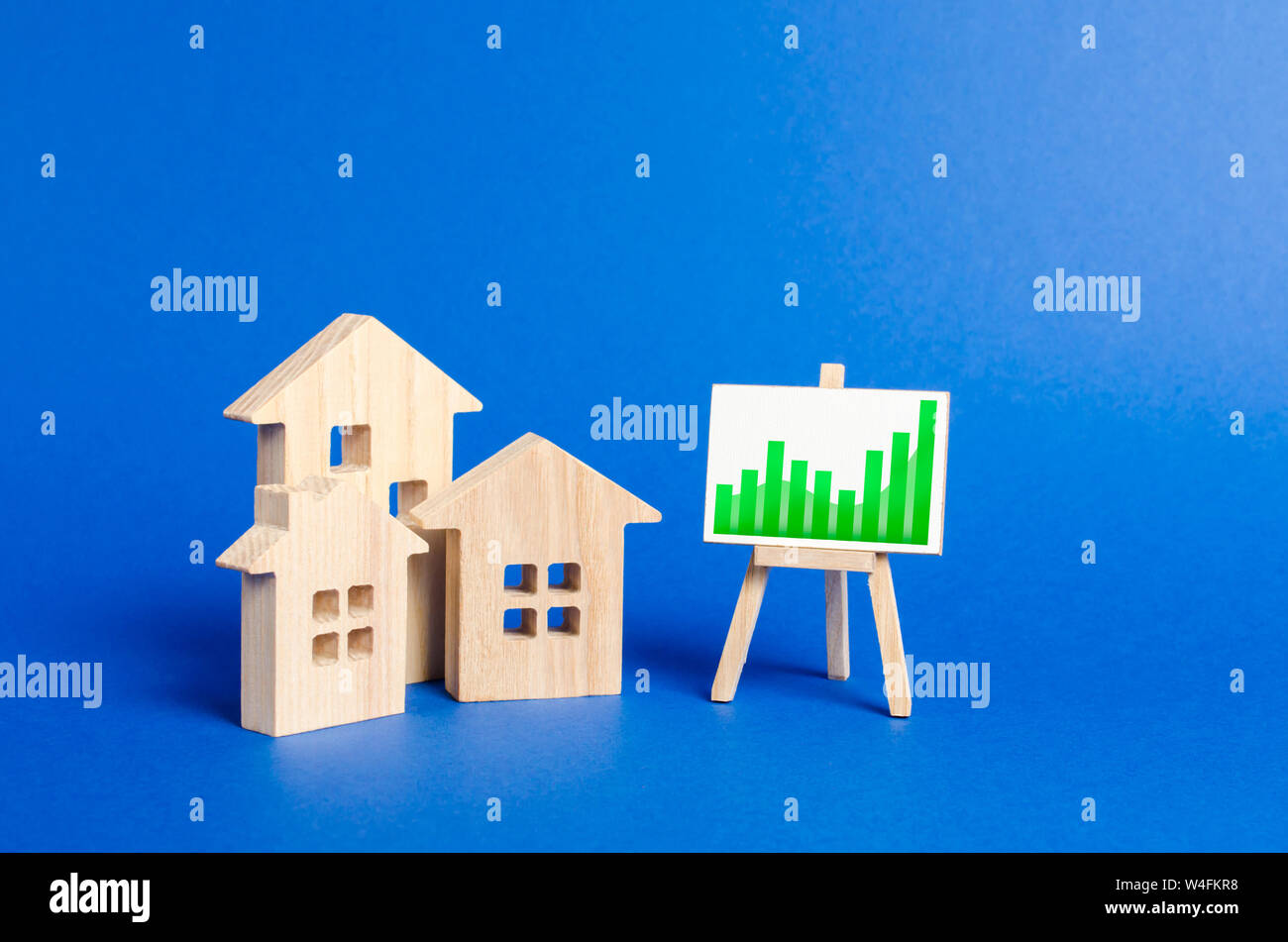 Trois maisons en bois et une tendance positive graphique sur un support. Augmenter la valeur de l'immobilier. Des taux élevés de construction, forte liquidité. L'offre et de la demande. Banque D'Images